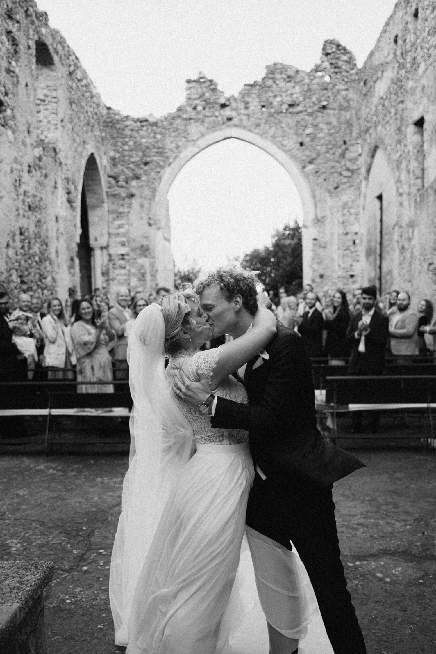 Black and white photograph of the newlyweds kissing after the ceremony