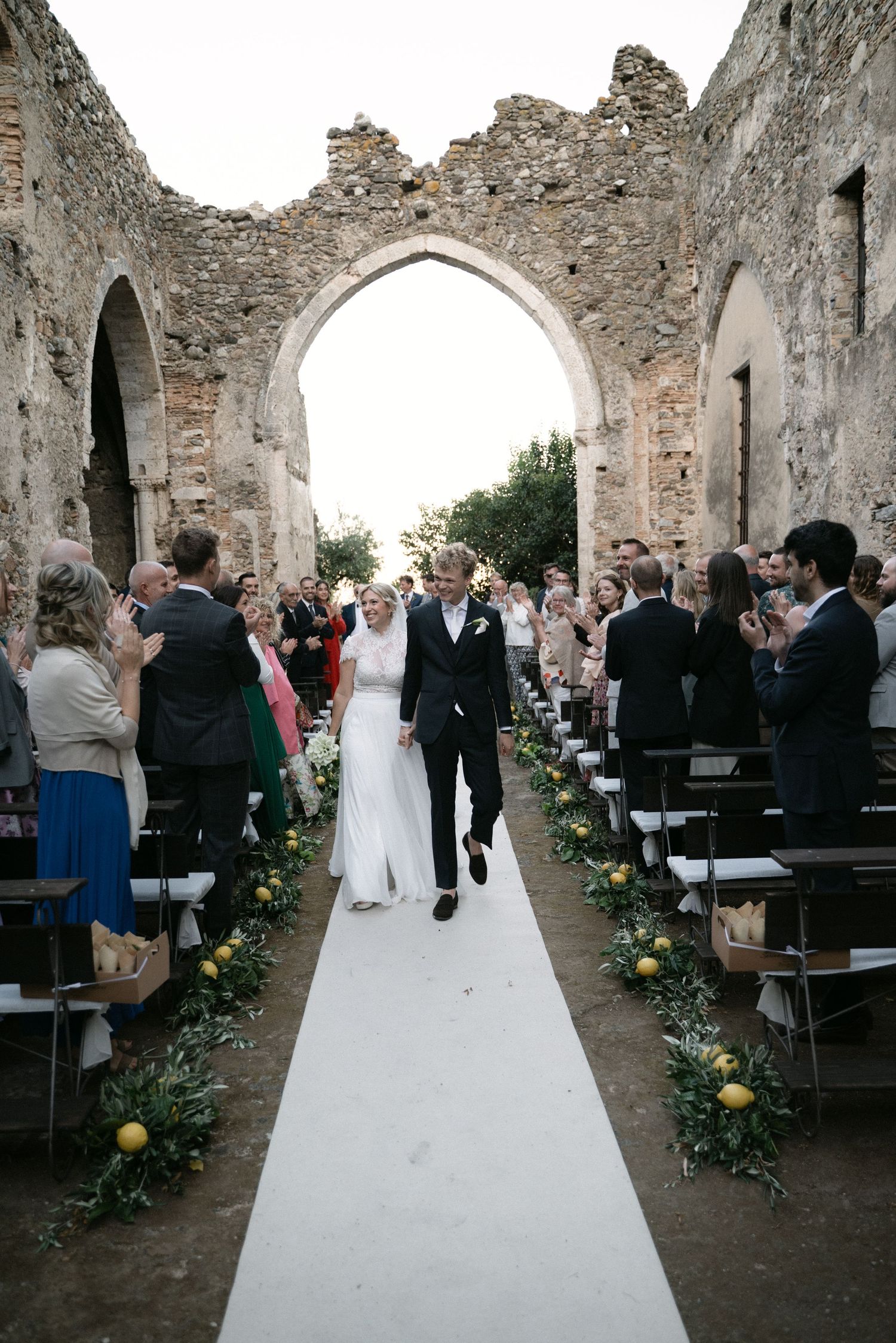 Newlyweds walking down the aisle as their guests applaud