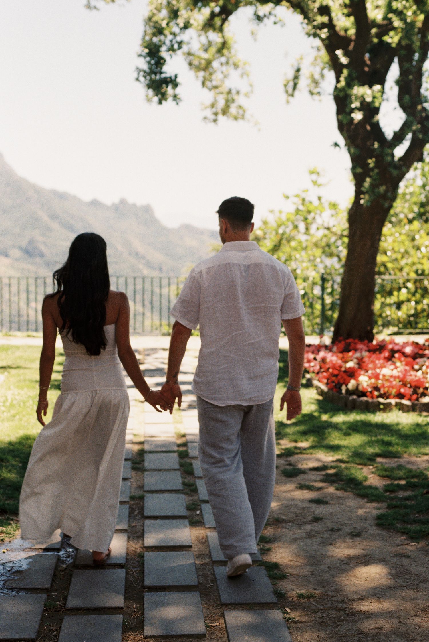 Newly engaged couple walking through a garden overlooking the Amalfi Coast