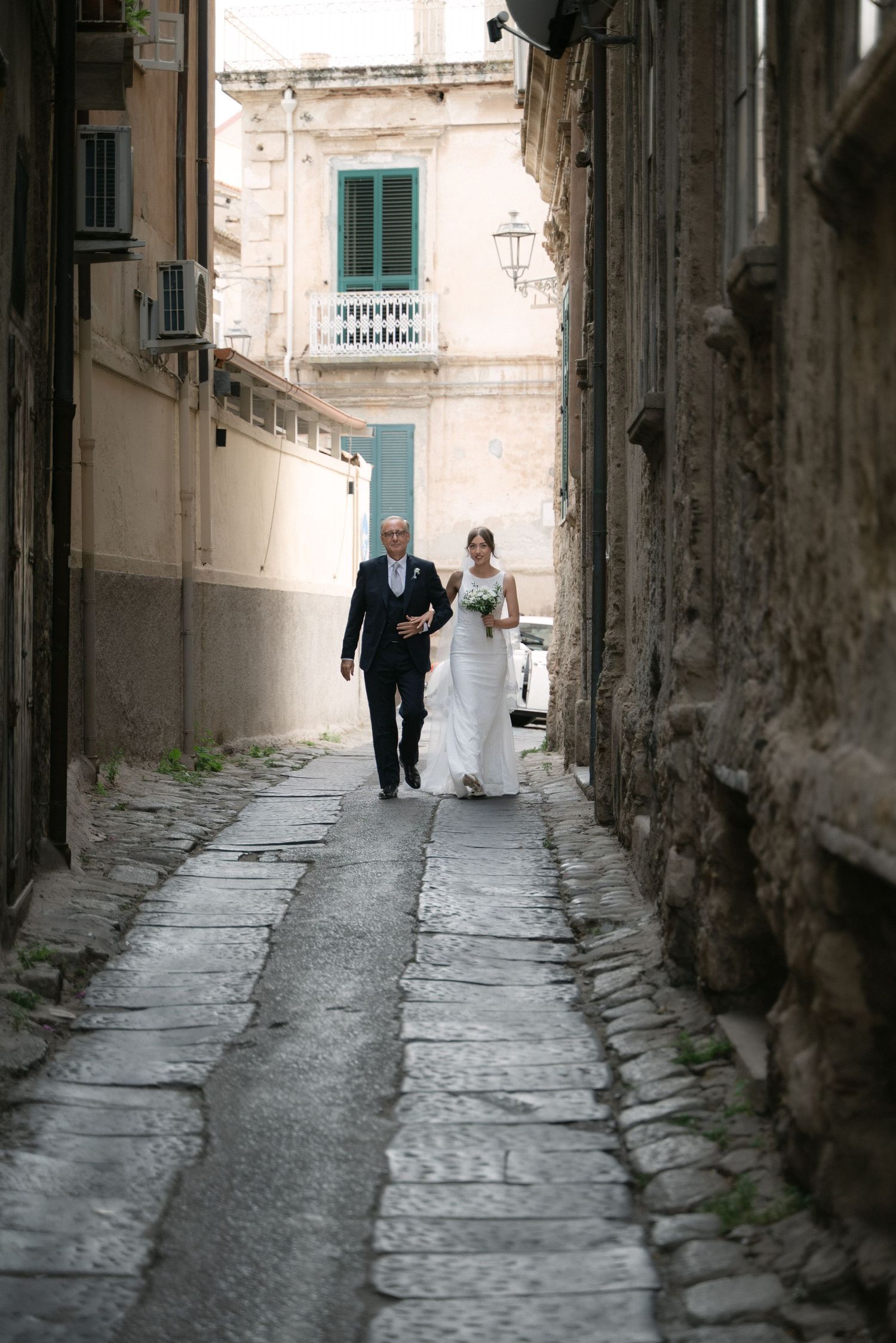 Bride walking with her father through the historic streets of Tropea