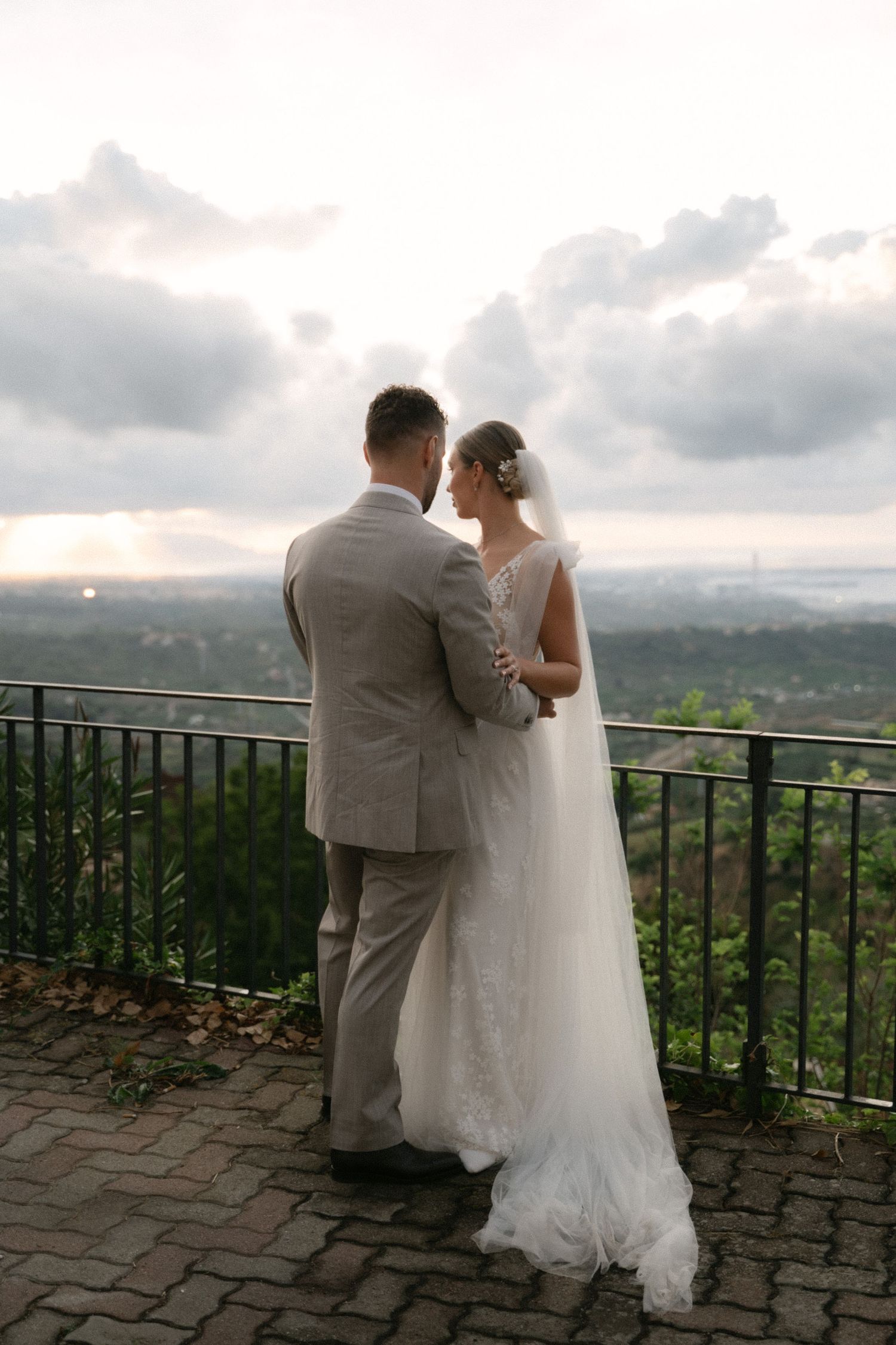 Bride and groom embracing above the Sicilian landscape
