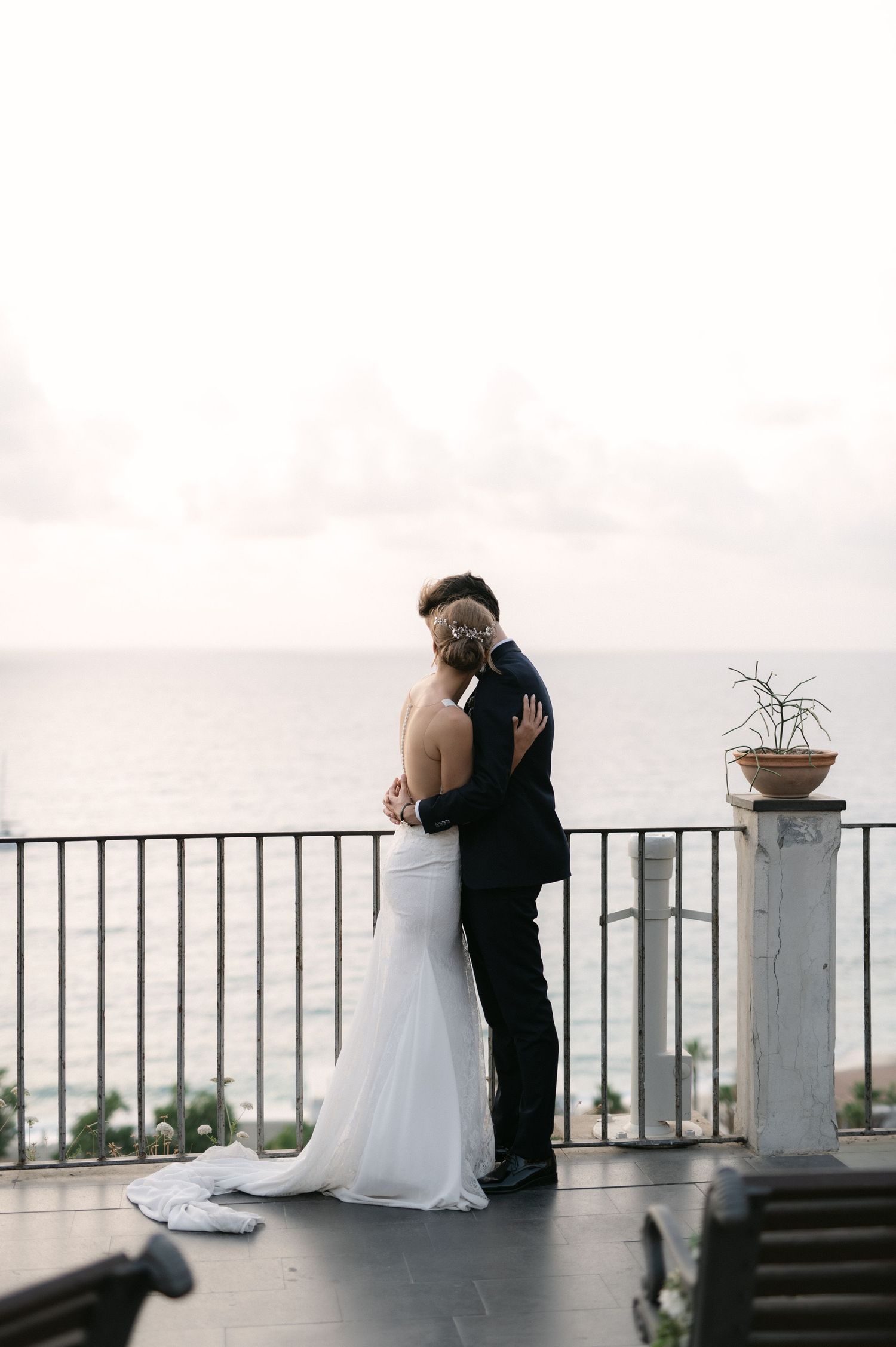 Giulia and Metz embracing on a terrace overlooking the Tropea coast