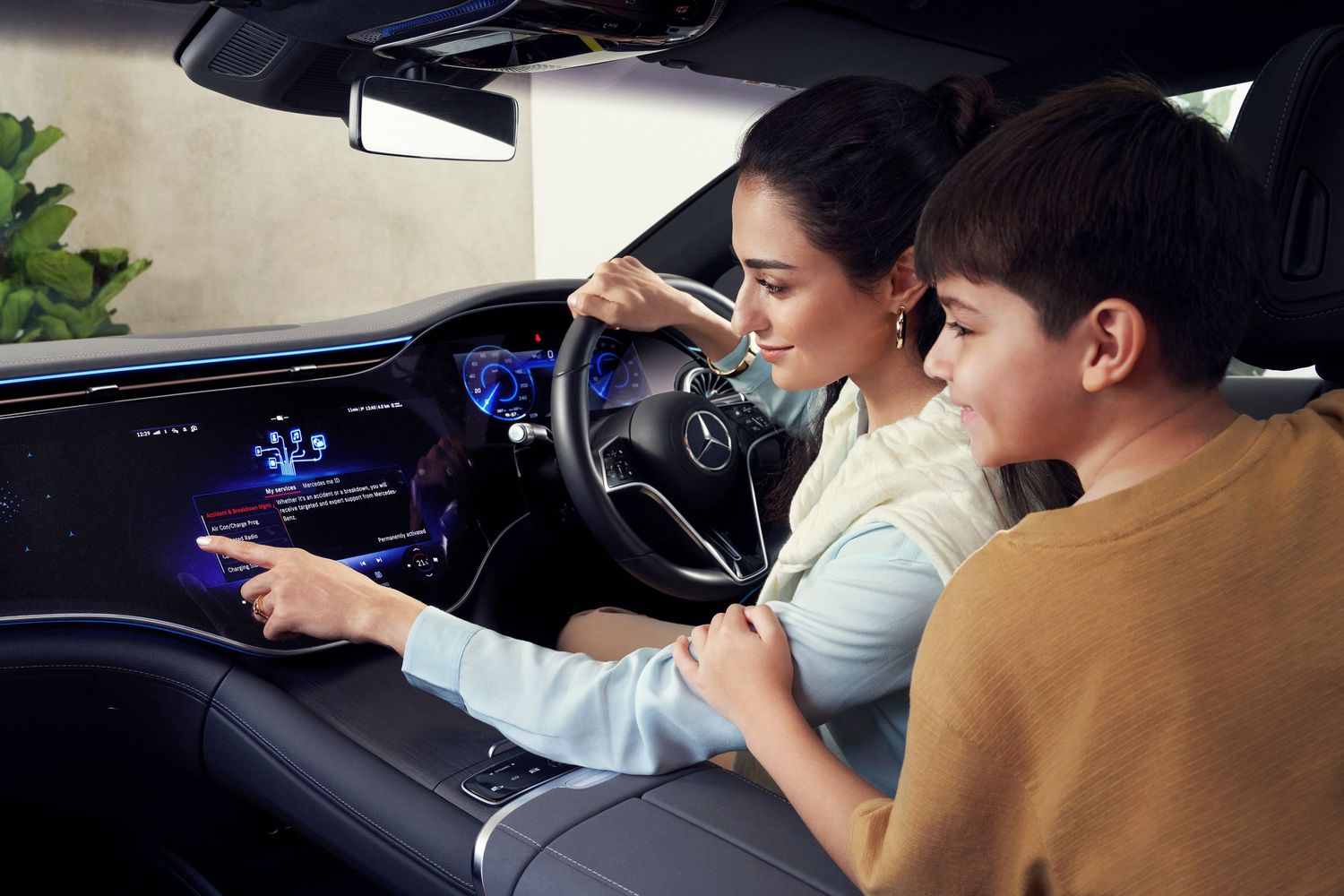 A woman and child explore the advanced touchscreen dashboard of a luxury Mercedes-Benz interior.