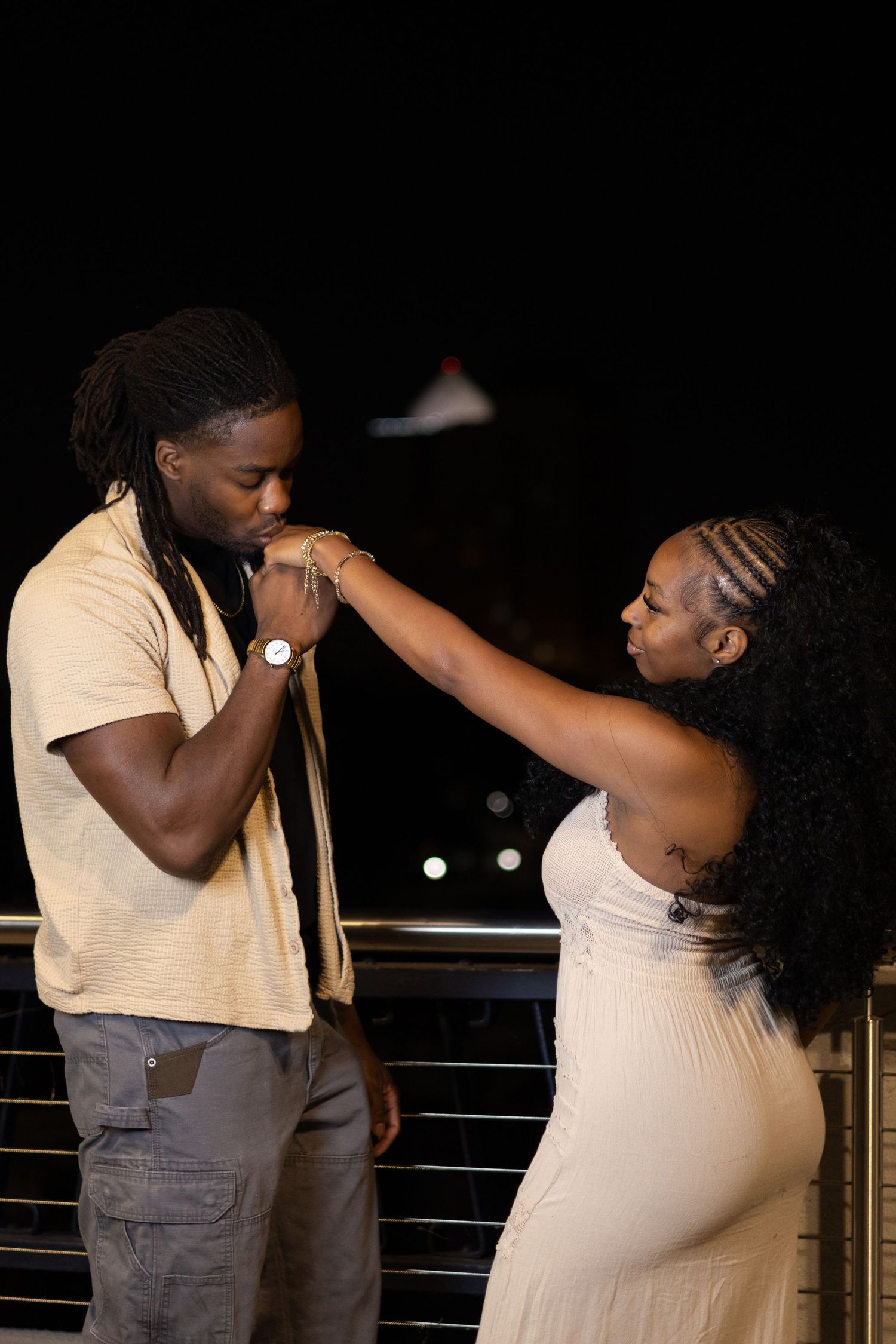 Black couple sharing romantic hand kiss moment at night outdoors.