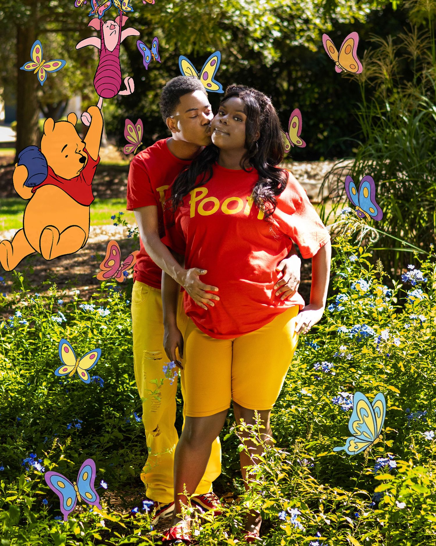 Couple in matching Winnie the Pooh red shirts embracing in a garden with colorful butterfly and Piglet decorations.