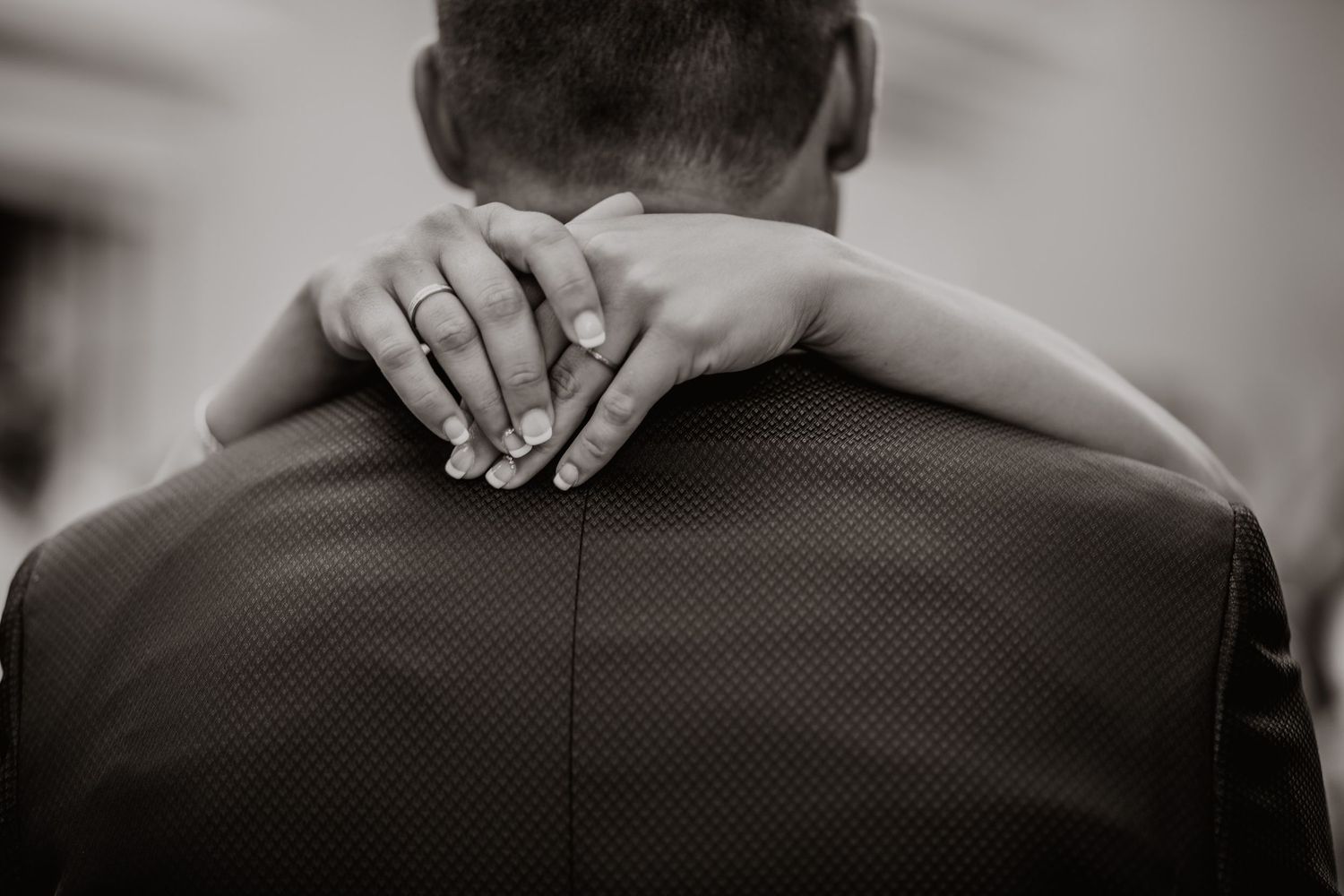 Foto en blanco y negro de la novia descansando su mano en el hombro de los novios que muestra el anillo de boda.