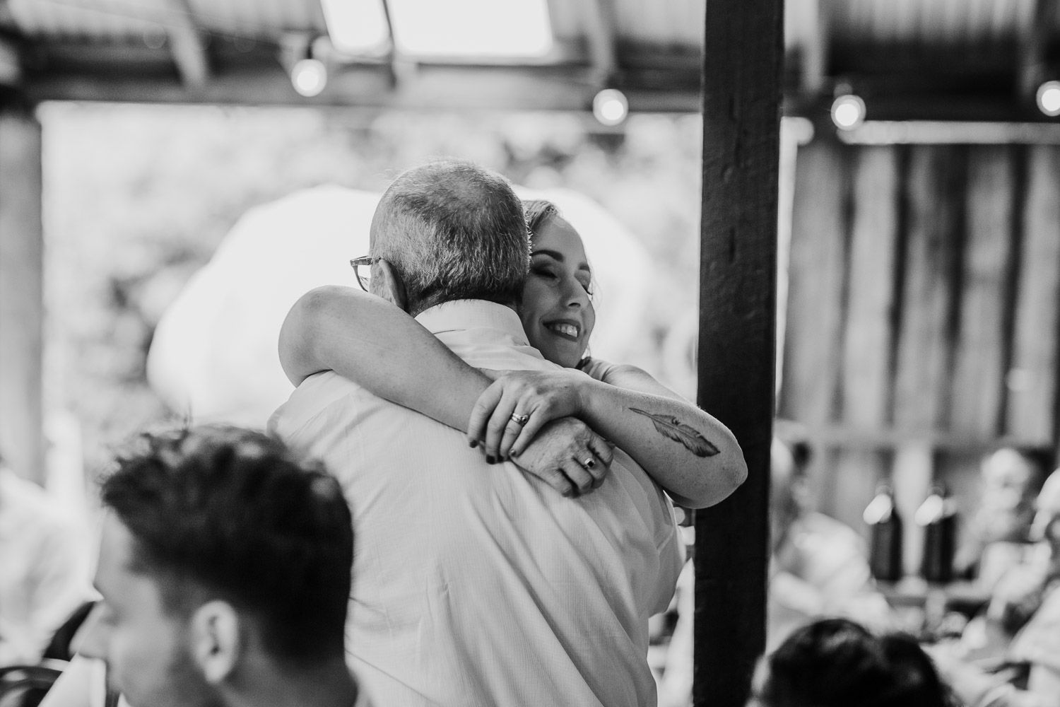 Emotional black and white photo of a bride sharing a warm hug with a wedding guest.