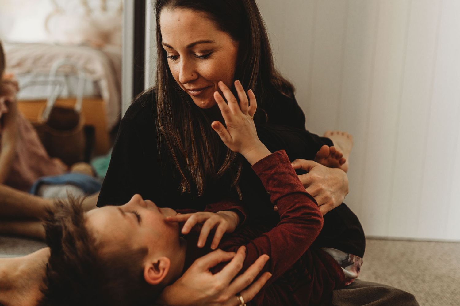 Loving mother smiling down at child lying in her lap during tender indoor moment.