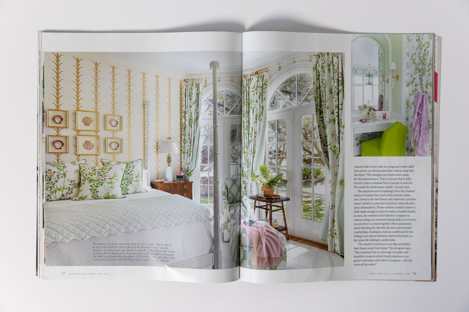 Magazine spread showing bright bedroom and sitting area with floral wallpaper and white furniture.