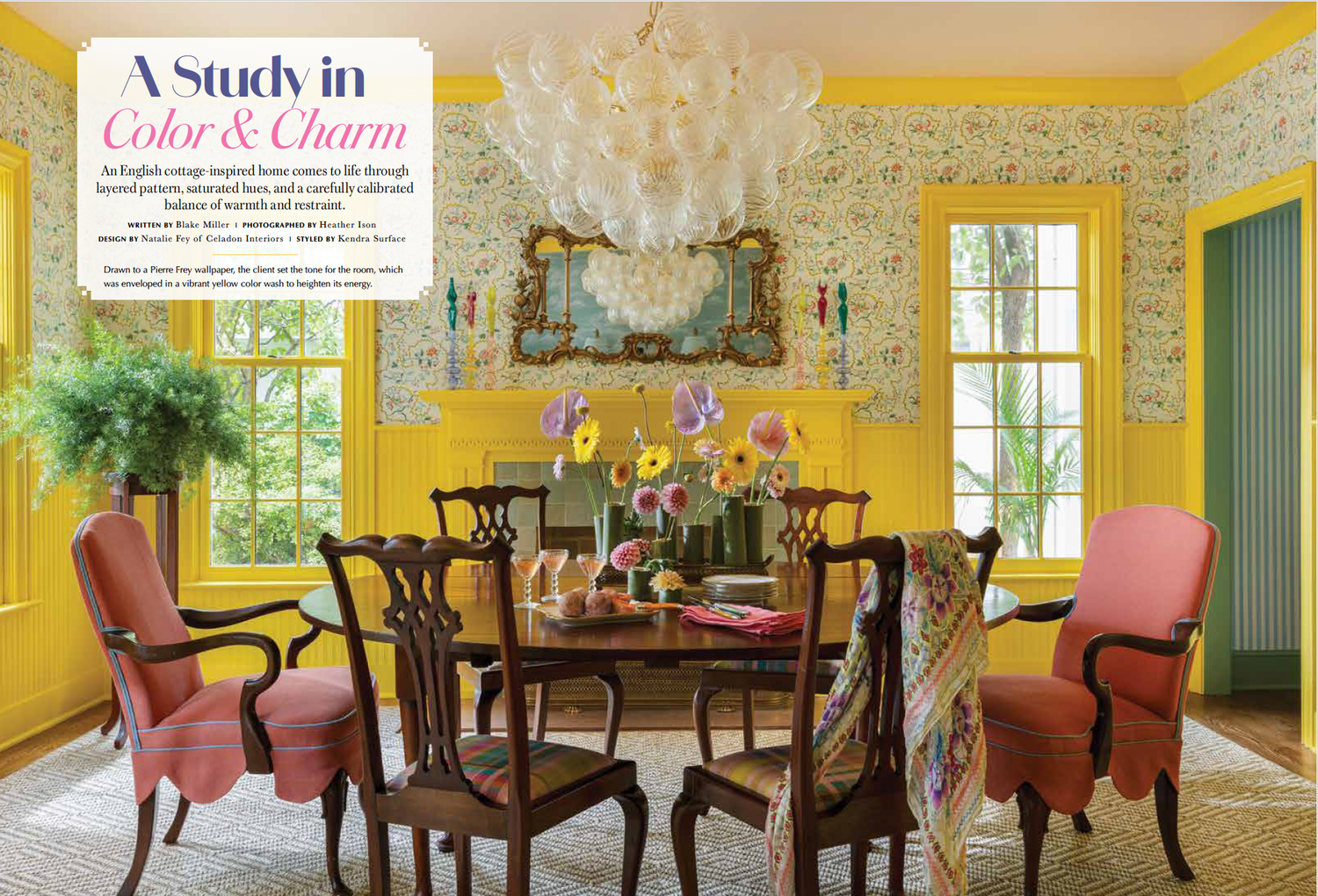 Vibrant yellow dining room with floral wallpaper, chandelier, mahogany table, and coral upholstered chairs in an elegant traditional style.