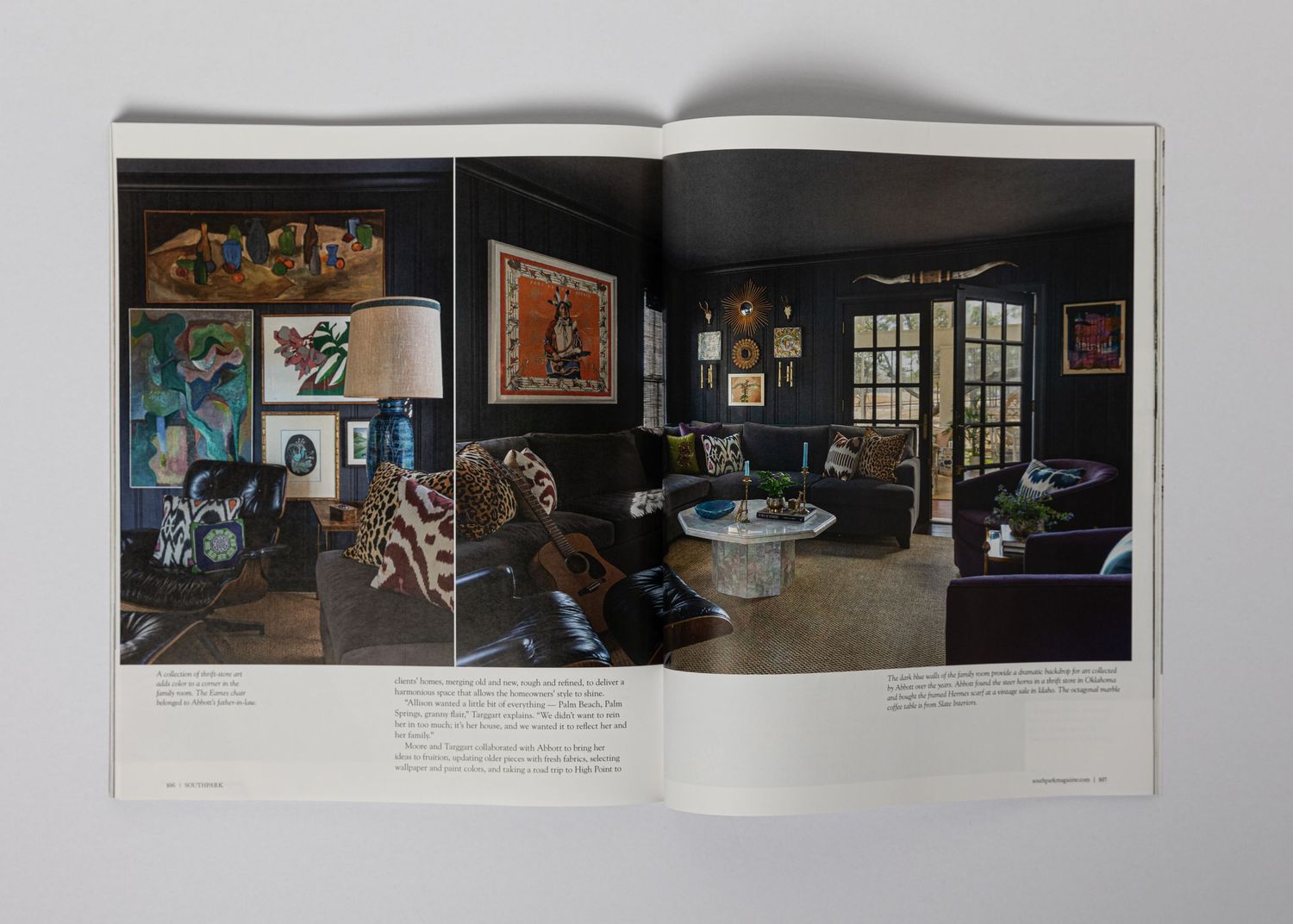 Magazine spread featuring dark-walled living room with eclectic art collection and modern furnishings.