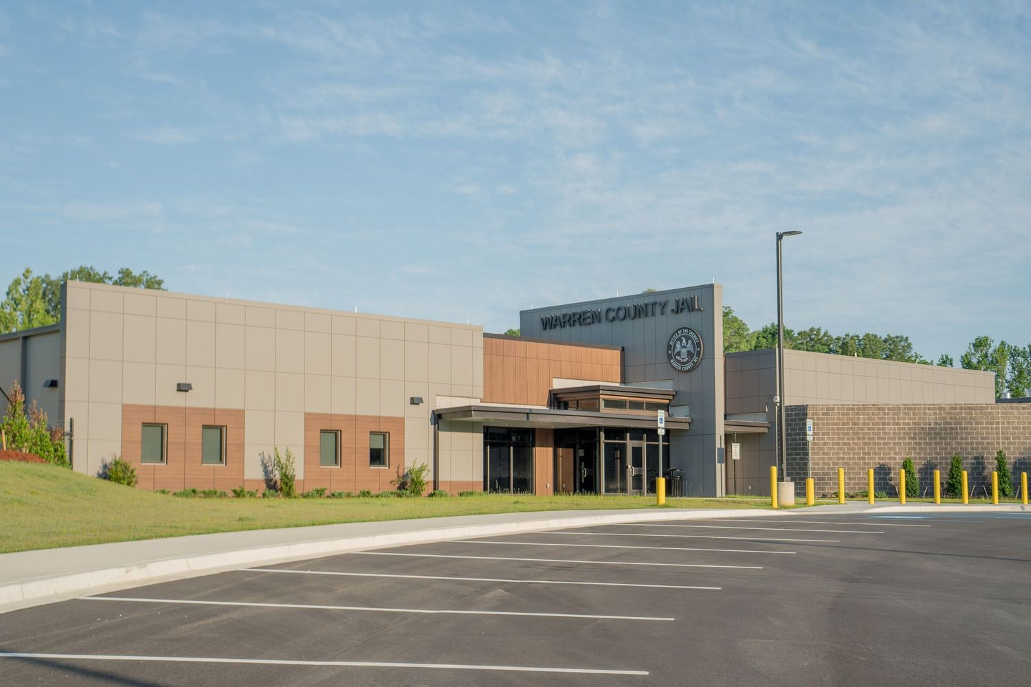 Exterior view of Warren County Jail building with modern brick facade, parking lot, and landscaped surroundings on a clear day.