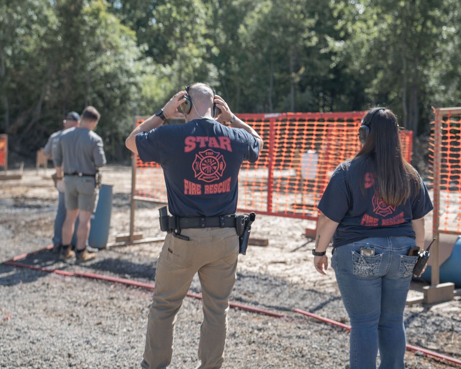 Star Fire Rescue team members in navy blue shirts observe a training exercise at an outdoor construction site.