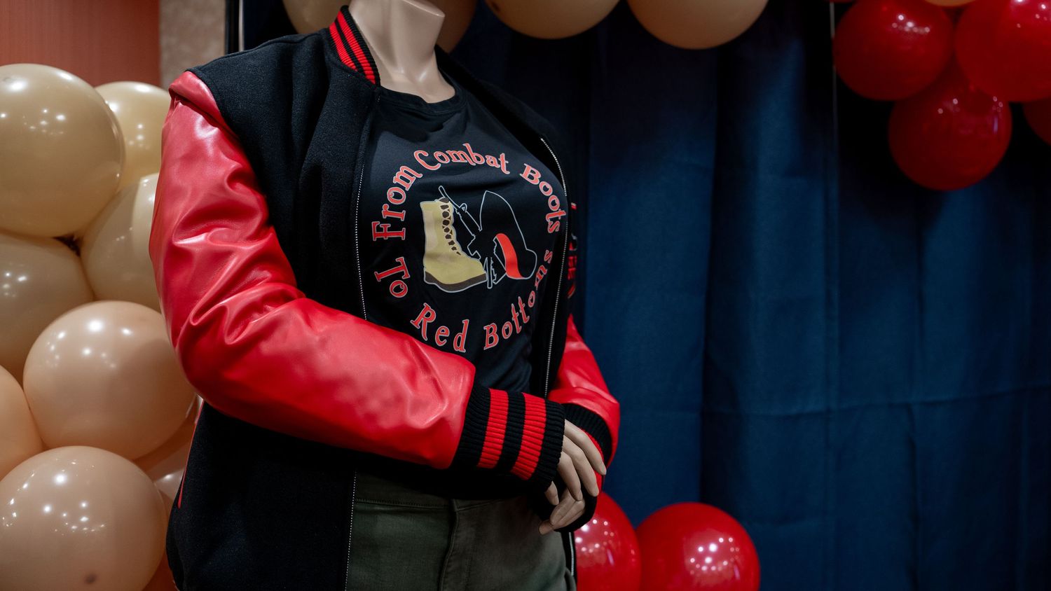 Mannequin wearing a black and red varsity jacket with balloon decorations in background.