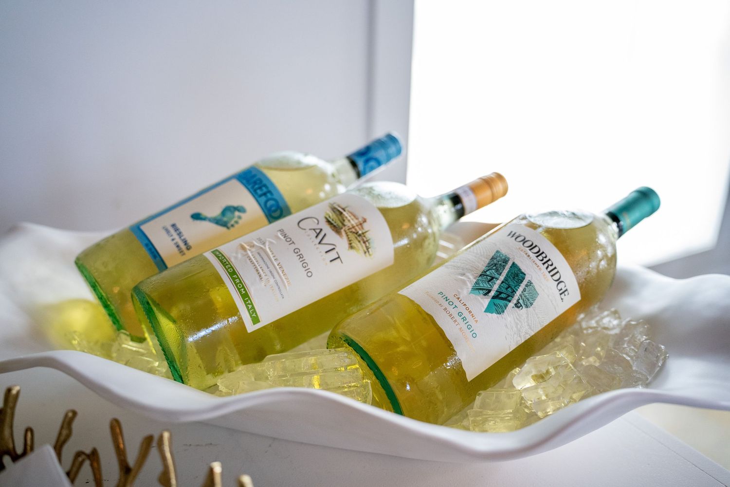 Two chilled white wine bottles, Cavit and Starborough, resting on ice in an elegant white serving tray.