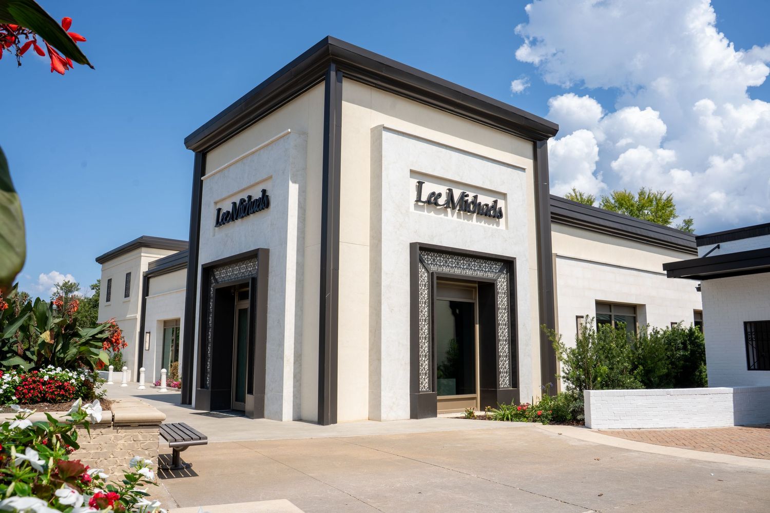 Exterior view of a Michaels craft store with modern white facade, dark trim, and manicured landscaping on a sunny day.