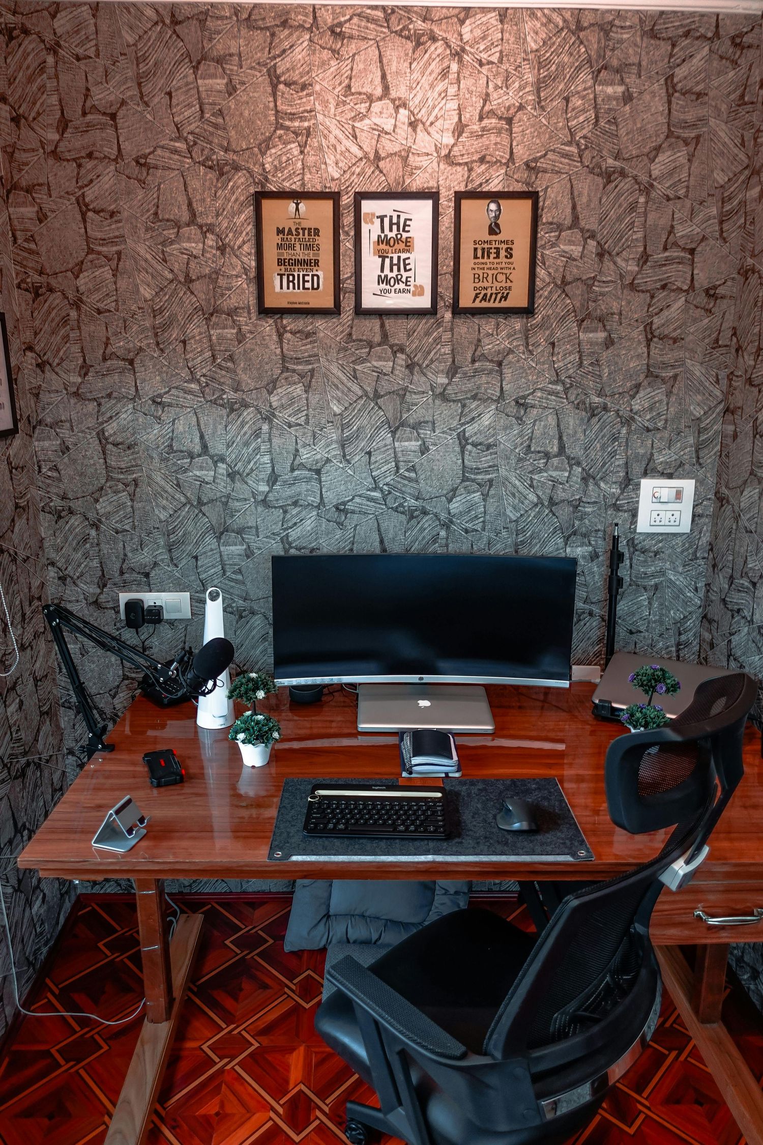 Modern home office setup with dual monitors, microphone, wooden desk, and motivational framed wall art.