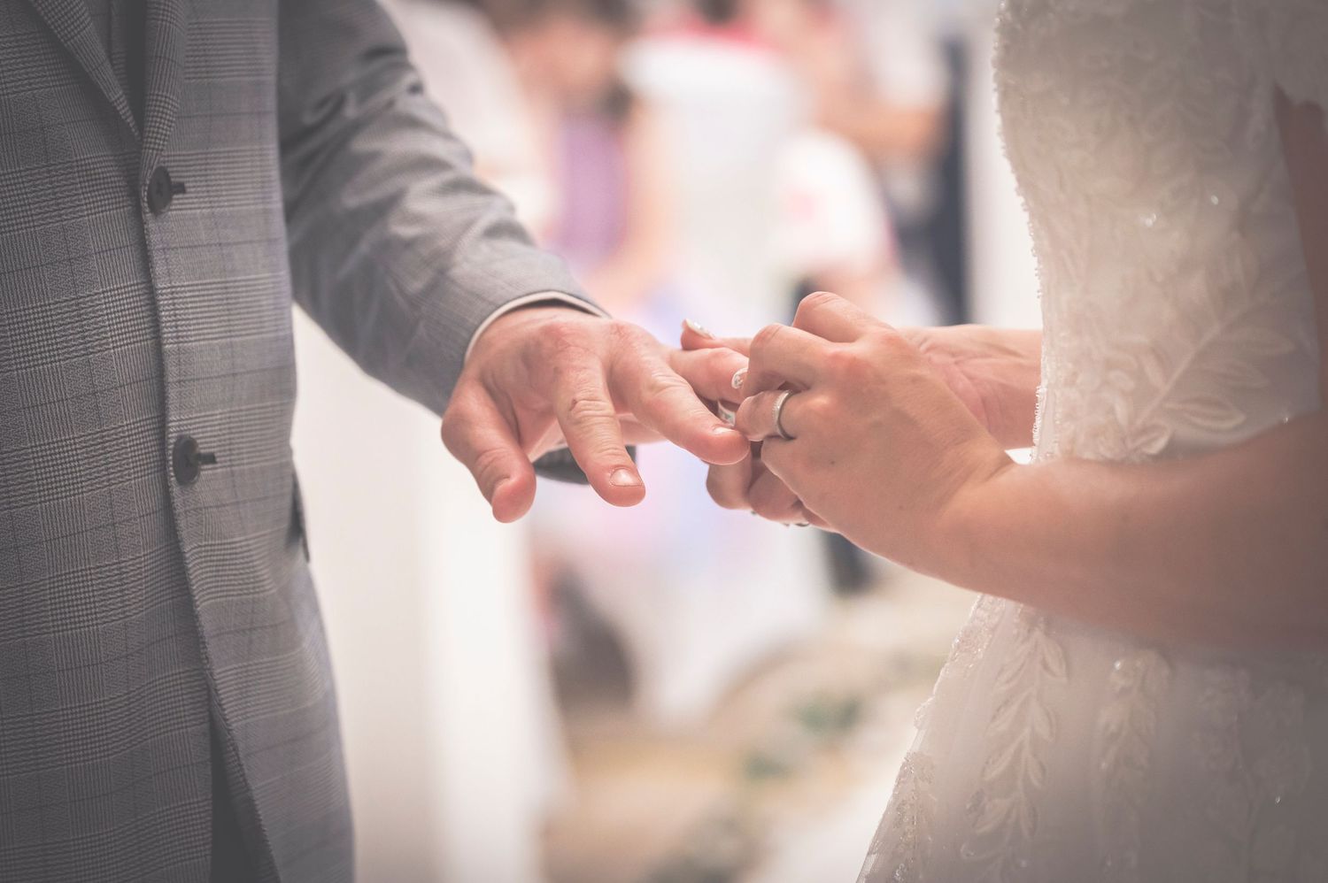 Bride placing wedding ring on grooms finger during intimate ceremony close-up.
