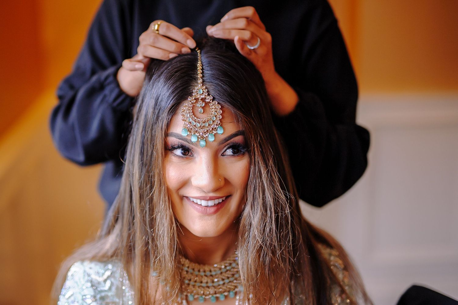 Close-up shots showing intricate bridal makeup and jewelry preparations in warm lighting.