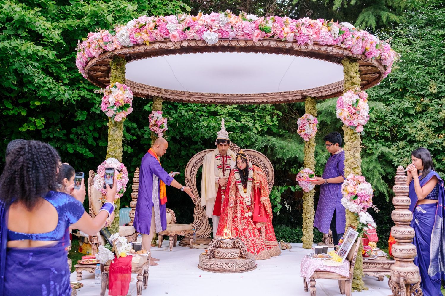 Decorated outdoor wedding venue with pink floral arrangements and traditional Indian elements.