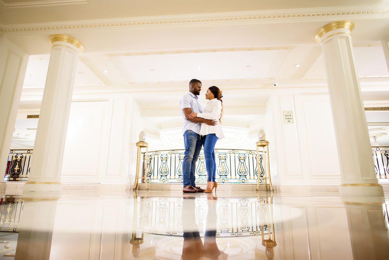 A casual couple shares a tender moment in a bright, airy space with elegant architectural details.