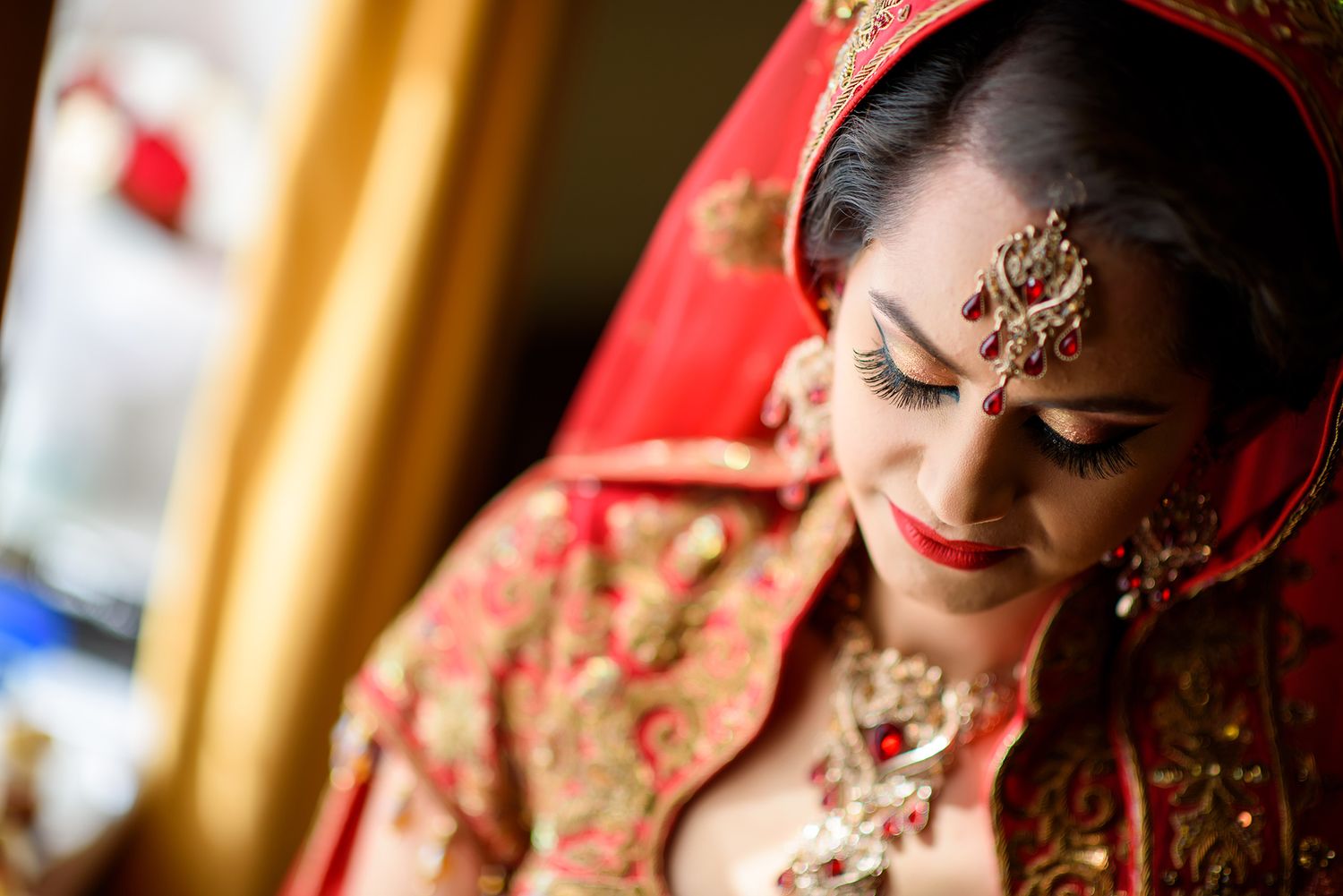 Close up of intricate bridal jewelry and makeup in traditional South Asian style.