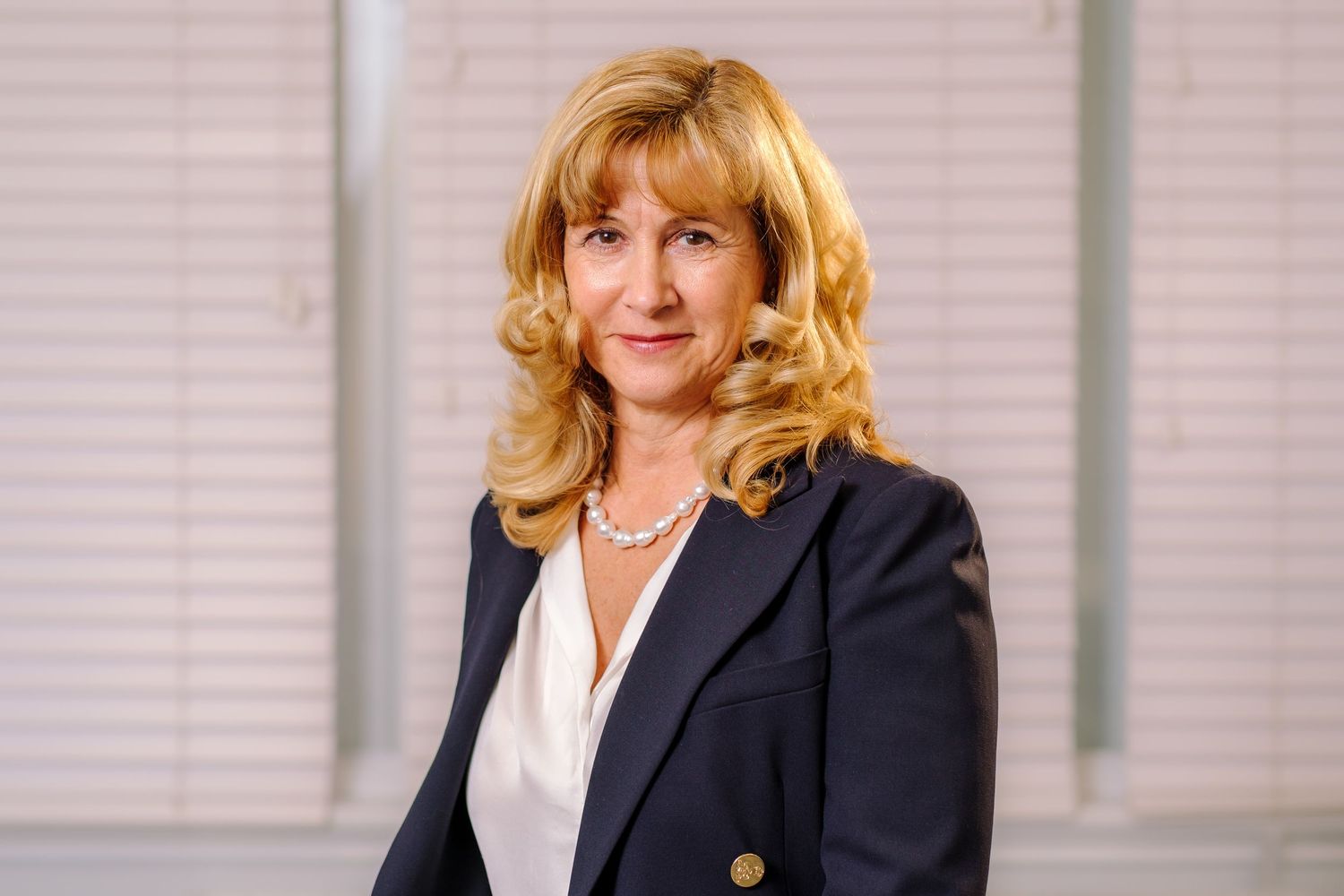 Professional headshot series of woman in black blazer against neutral background.