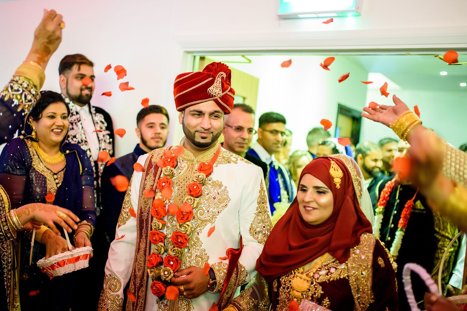 Joyous celebration at an Indian wedding with guests wearing traditional red and gold attire.