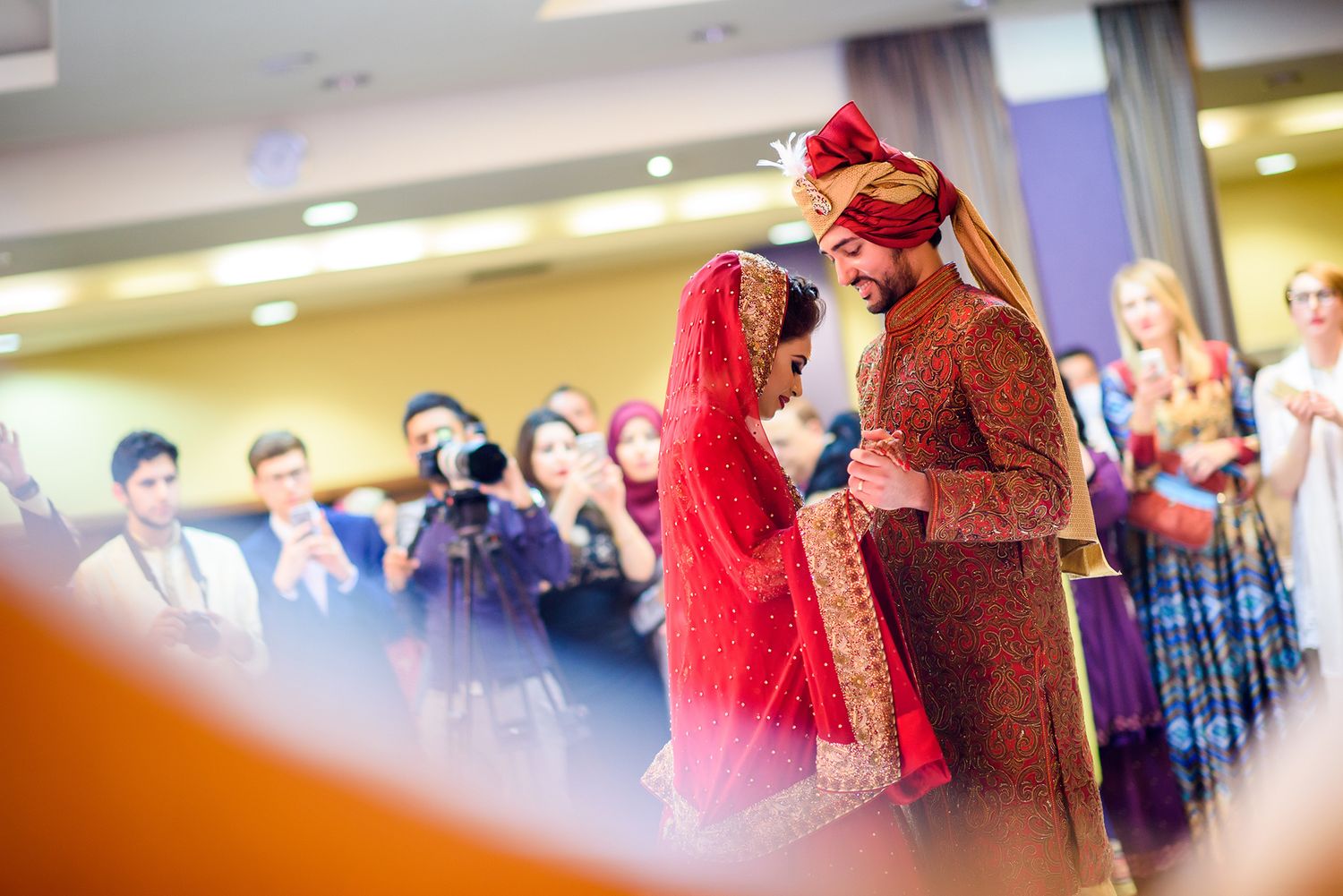 Wedding celebration in an indoor venue with guests watching a traditional ceremony.