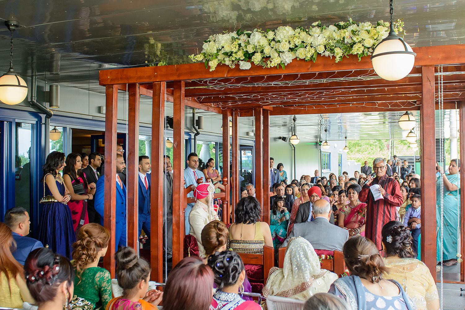 Large group of wedding guests gathered in a decorated indoor venue with blue and white accents.