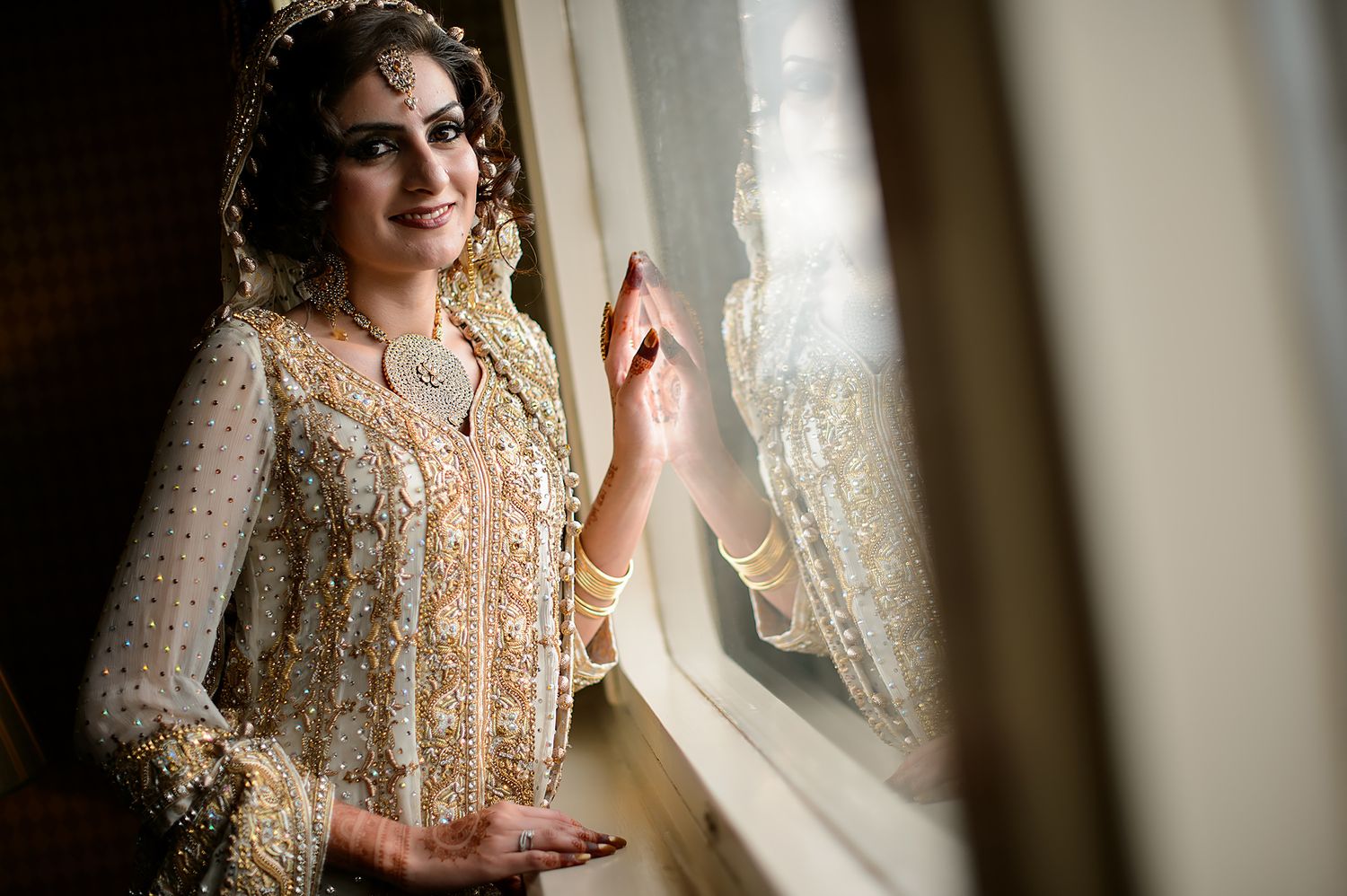 Soft-focus portrait through window light featuring elegant bridal attire.