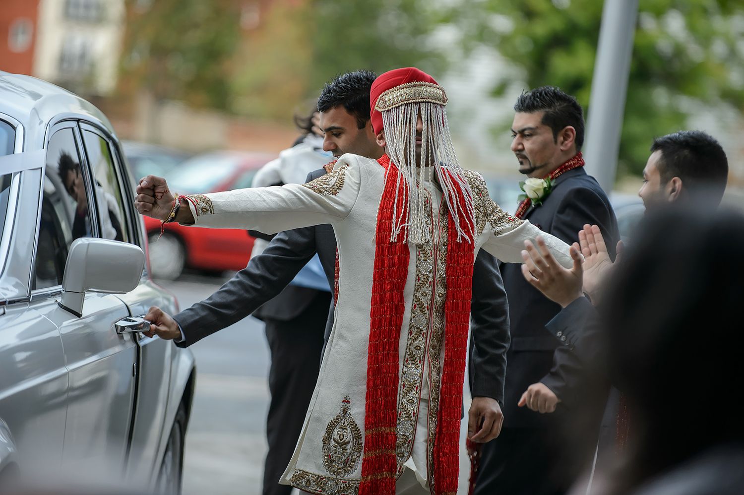 Wedding guests interact and socialize outside a building during a celebration.