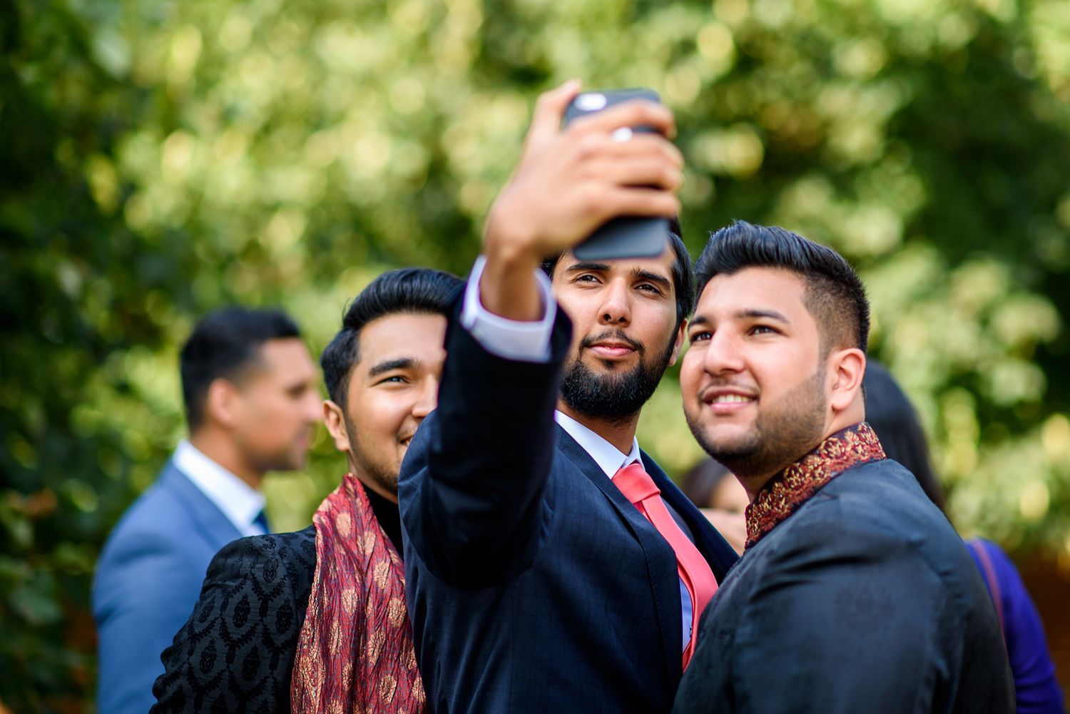 Outdoor wedding gathering with guests enjoying candid moments in natural lighting.