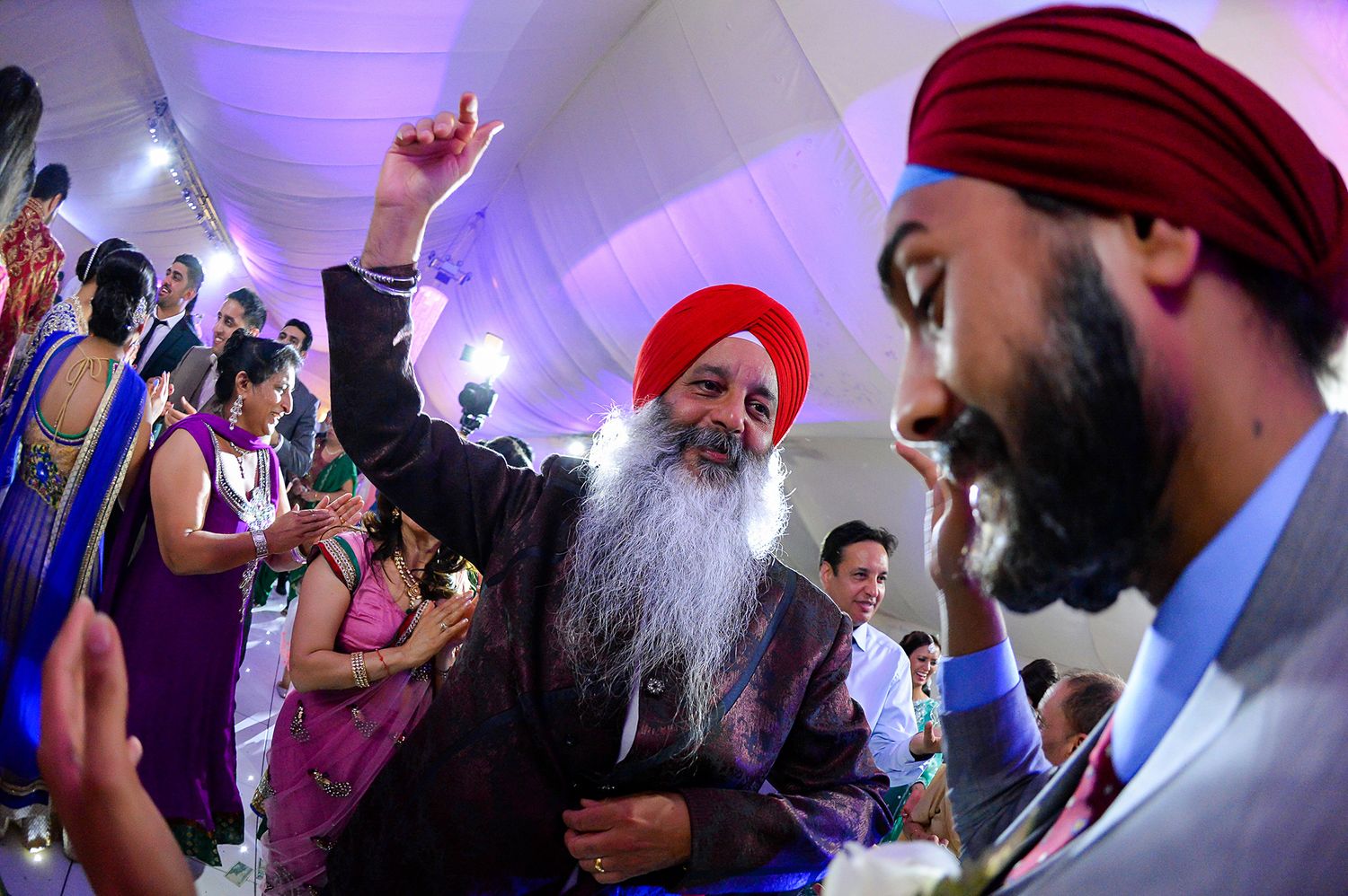 Sikh wedding guests dancing and celebrating with traditional turbans and festive attire.