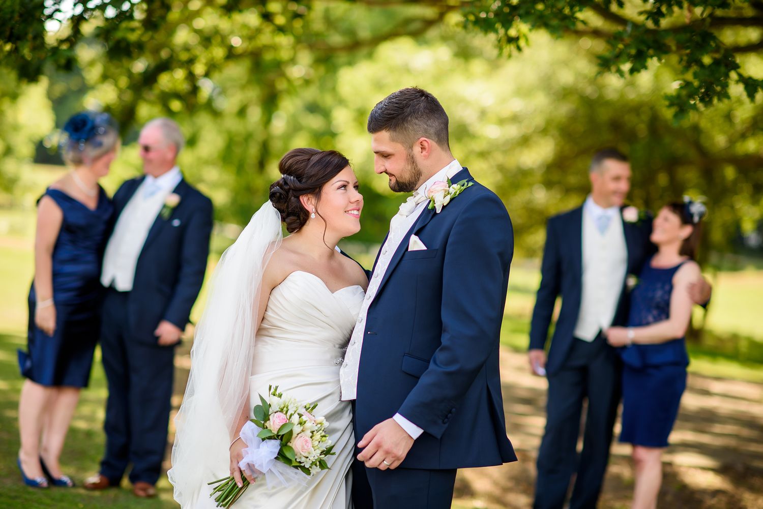 Romantic outdoor wedding photos captured under the dappled sunlight of a tree canopy.