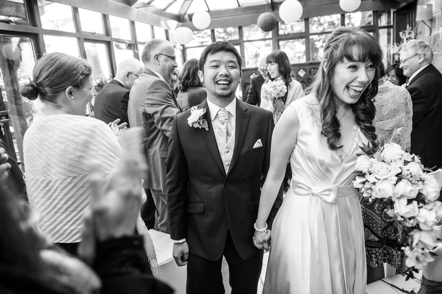 A wedding celebration in a church hall with guests and a beautiful floral bouquet.