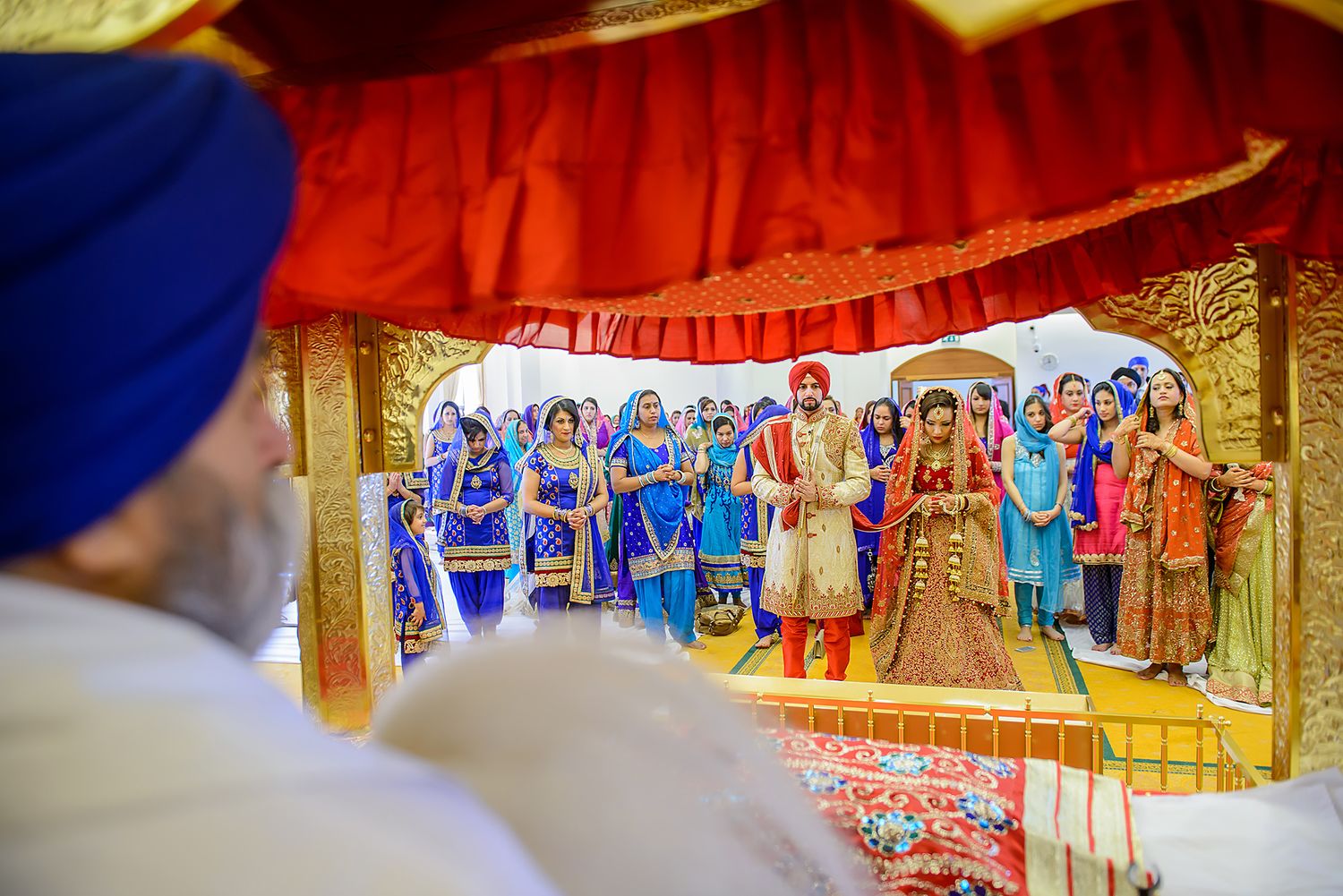Panoramic view of wedding guests in colorful Indian attire seated during traditional ceremony.