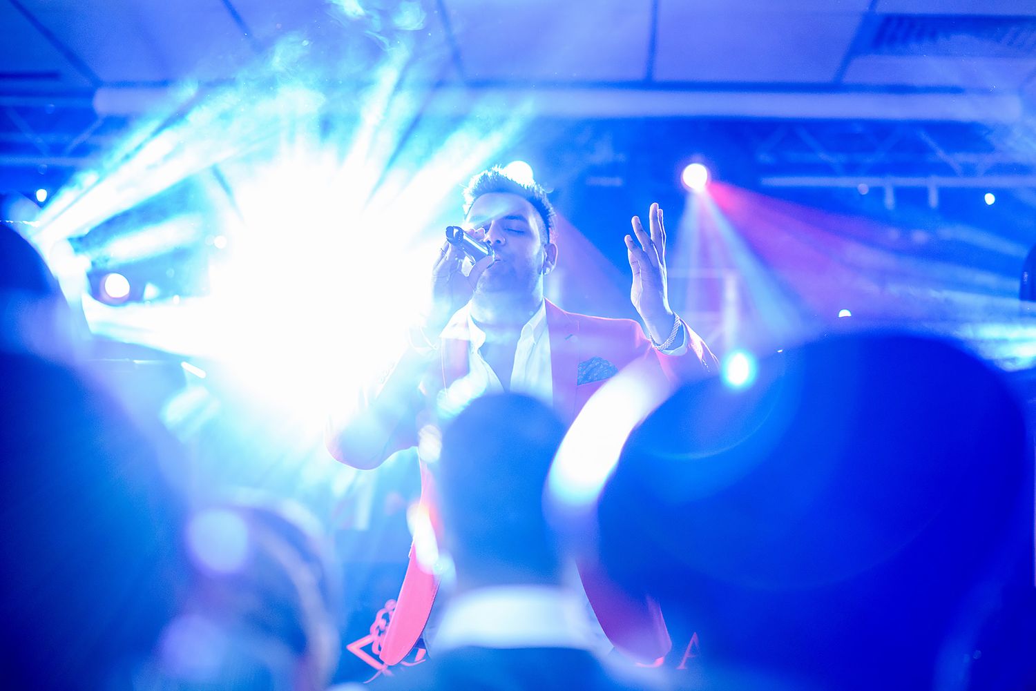 Blue stage lighting creates dramatic atmosphere at an indoor event.