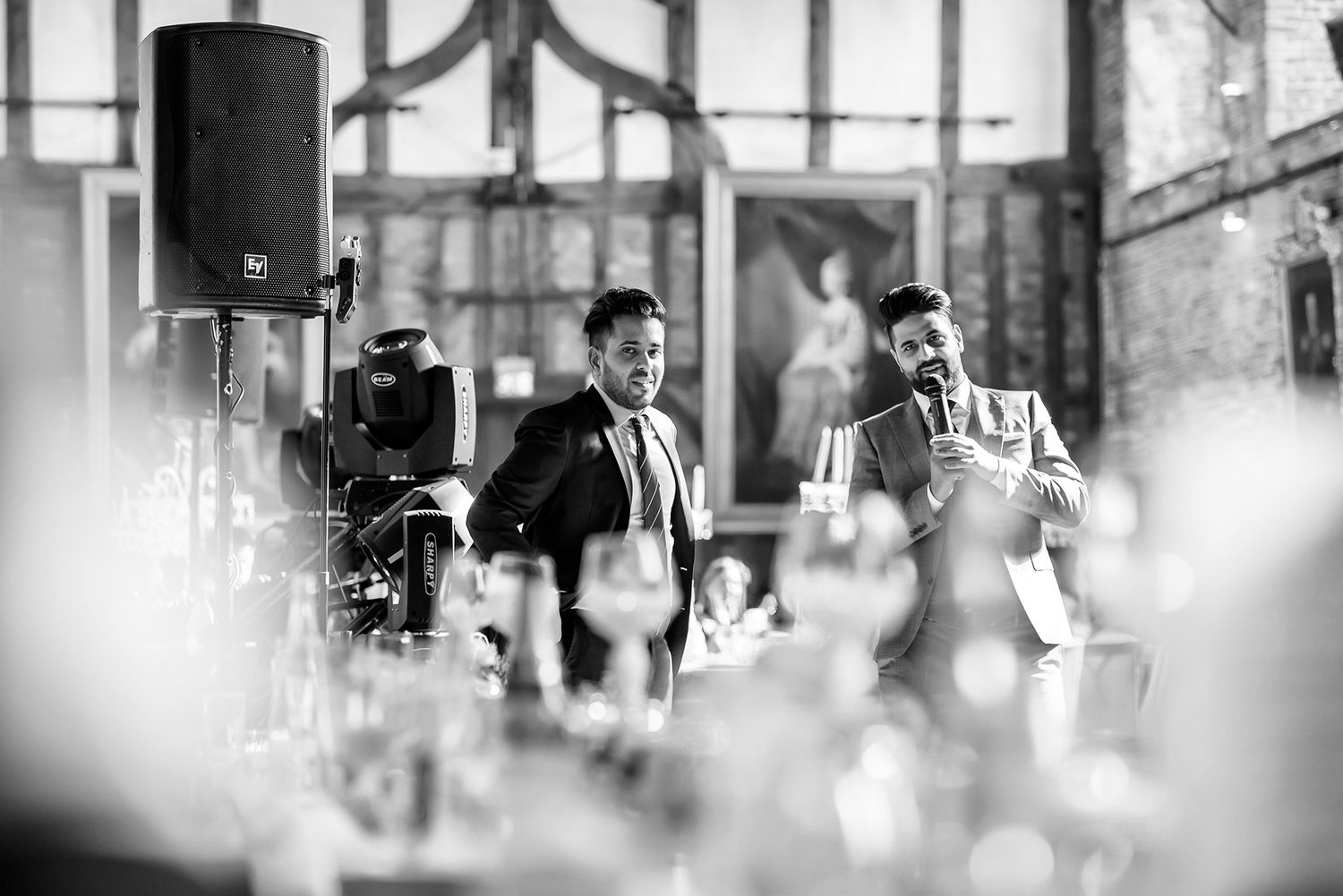 Black and white photograph of wedding speeches with guests seated at tables.