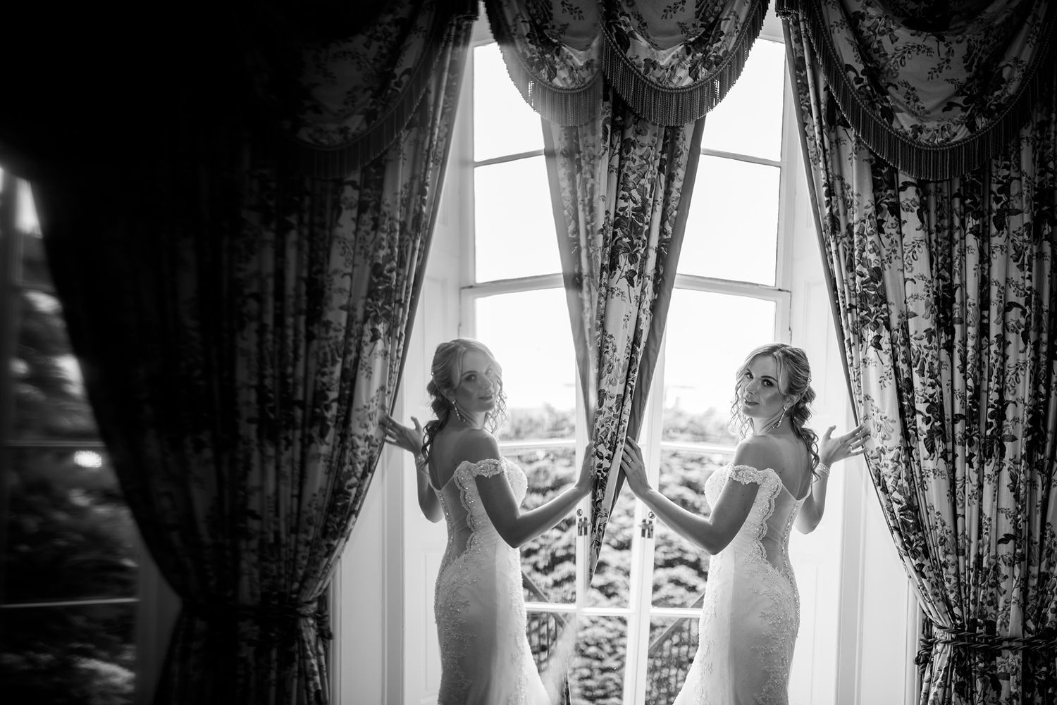 Silhouette of two figures by elegant curtained windows in black and white.