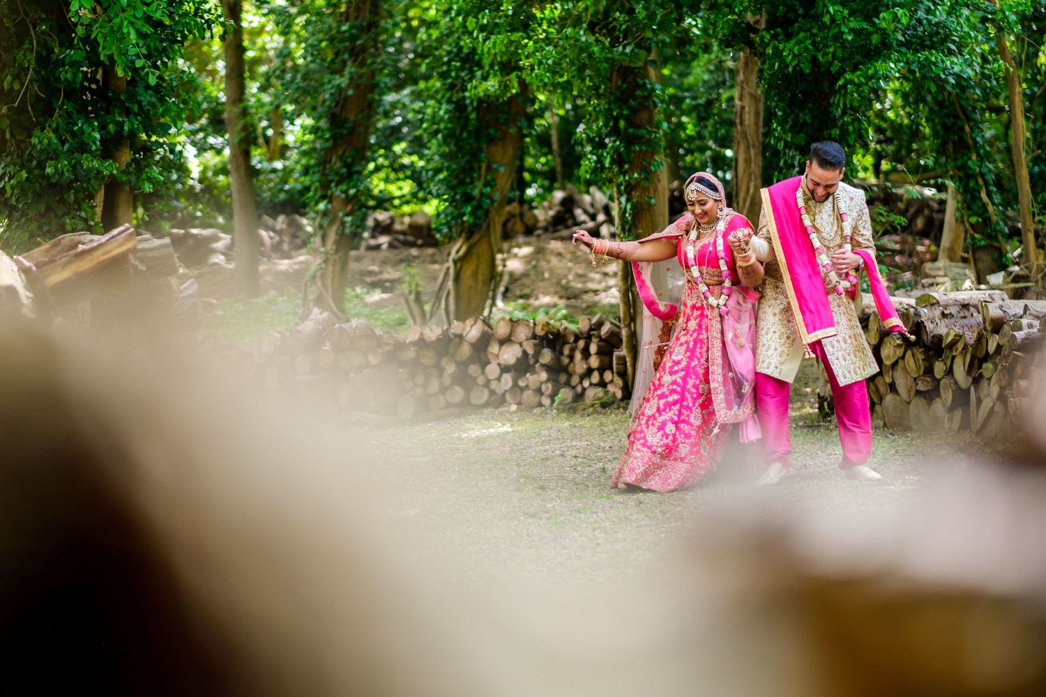 Outdoor wedding ceremony setting with lush green foliage and pink decorative elements.