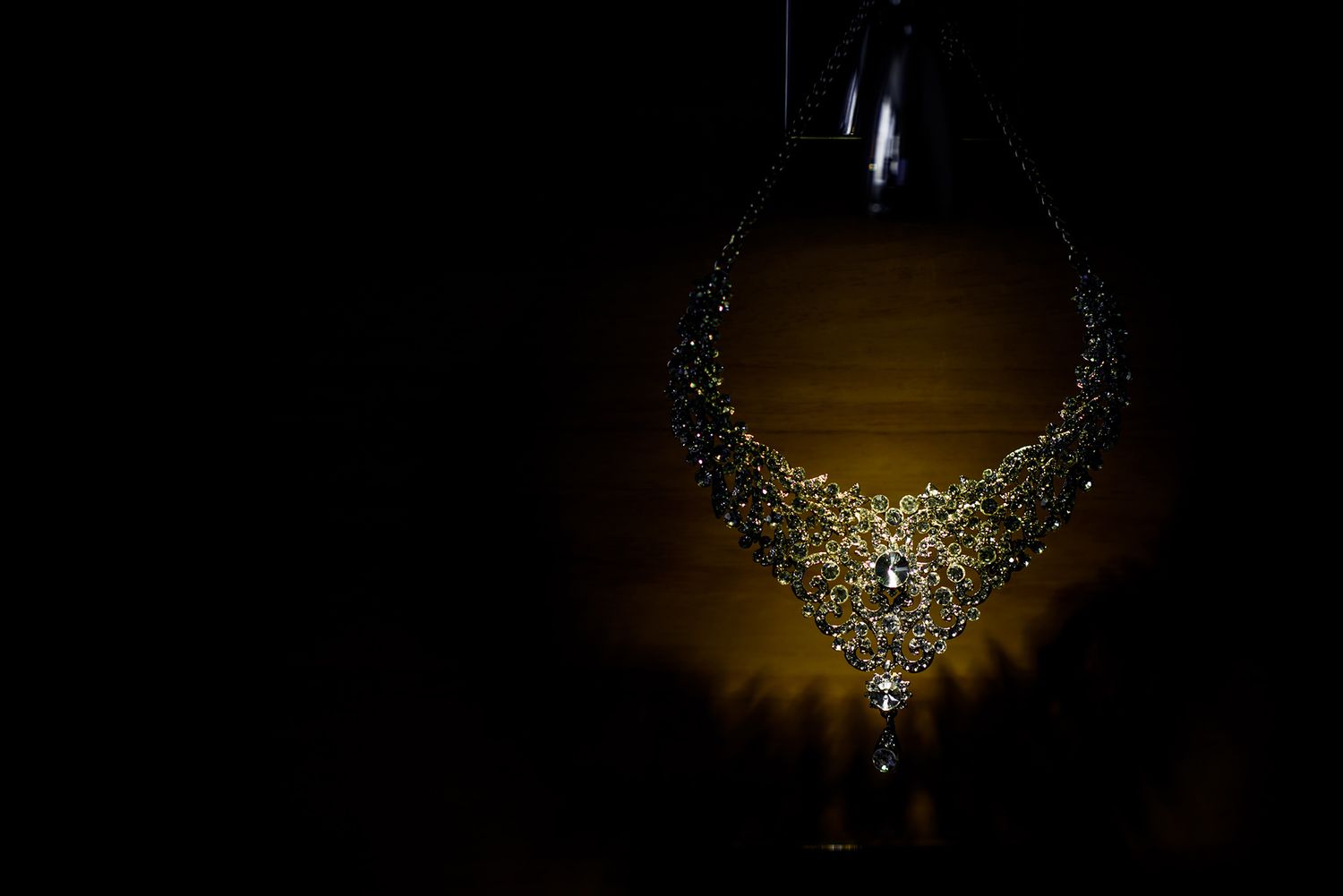 Silhouette of crystal chandelier details illuminated against dark background.