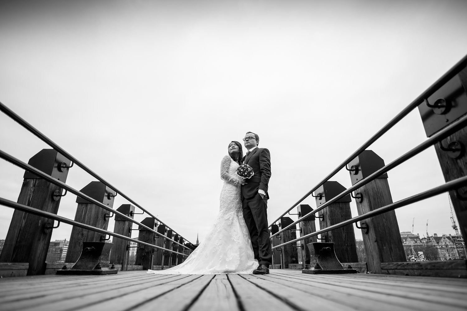 An artistic wide-angle wedding photo taken on London's Millennium Bridge.