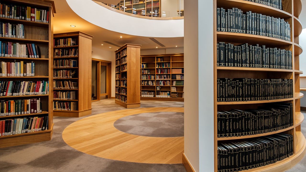 Modern library interior with curved wooden floors and circular shelving design.