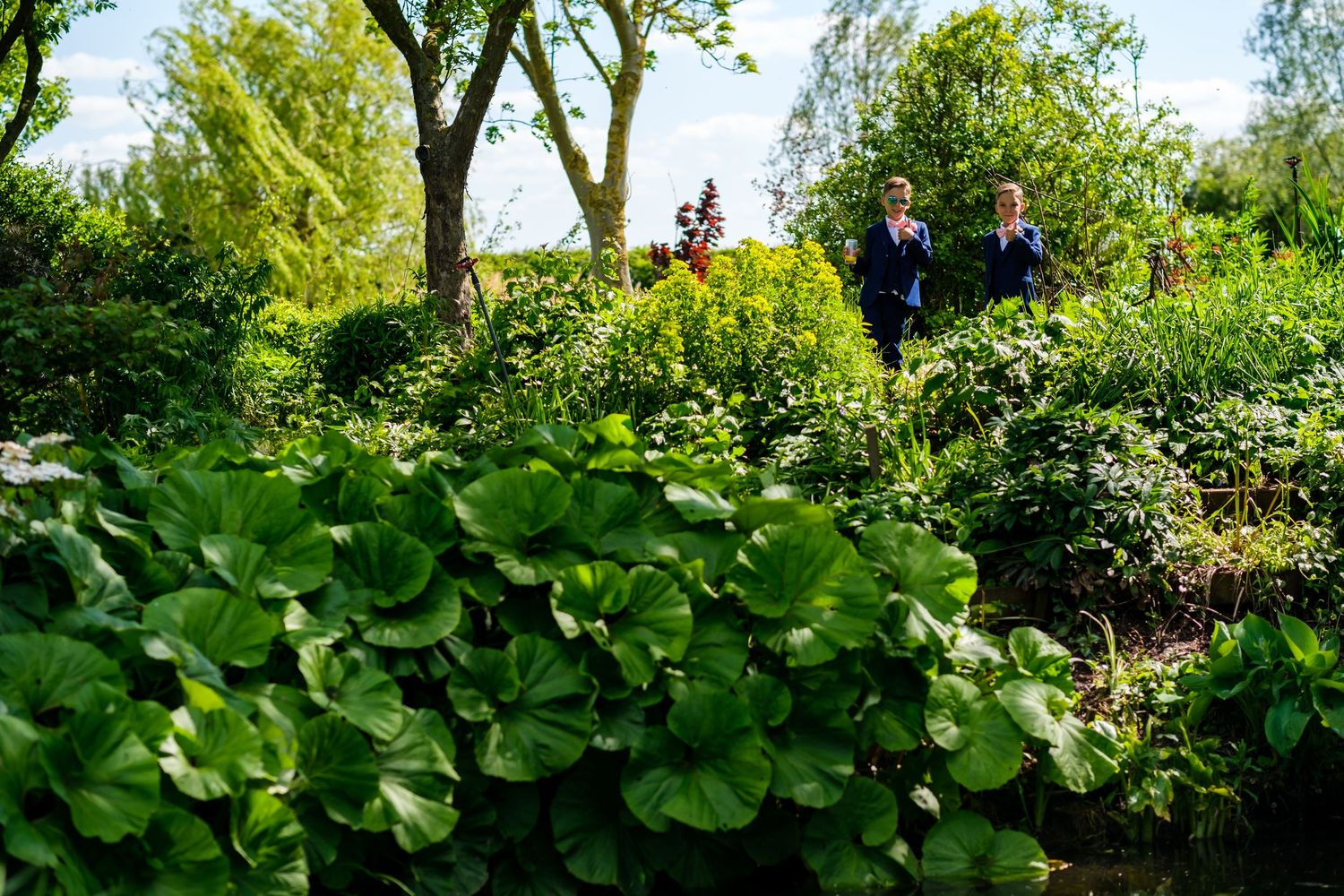 Lush garden pathway with green trees and foliage creating a natural archway.
