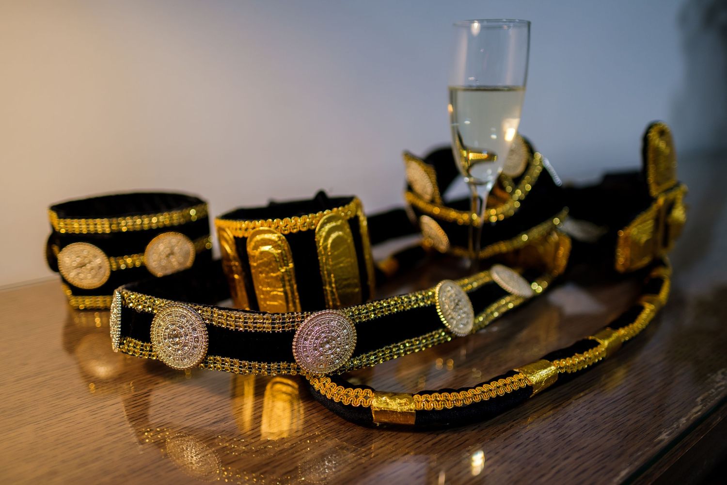 Close-up details of an elegant black and gold championship wrestling belt with ornate metallic designs.