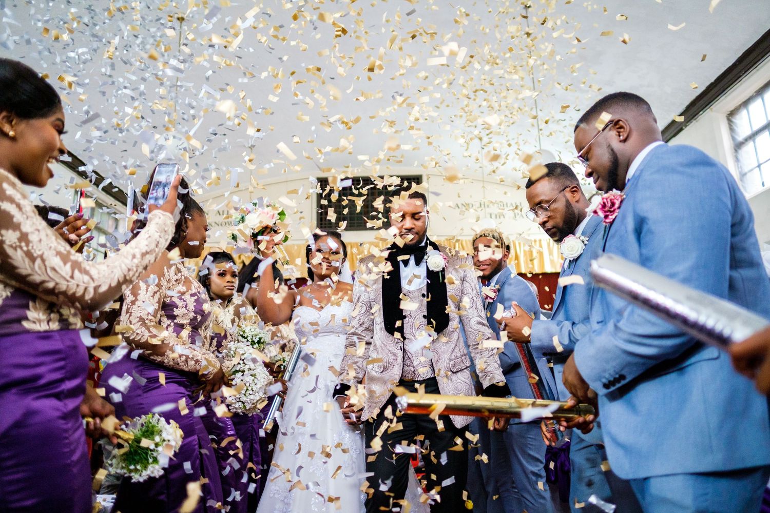 Wedding celebration with confetti raining down as guests celebrate joyfully.