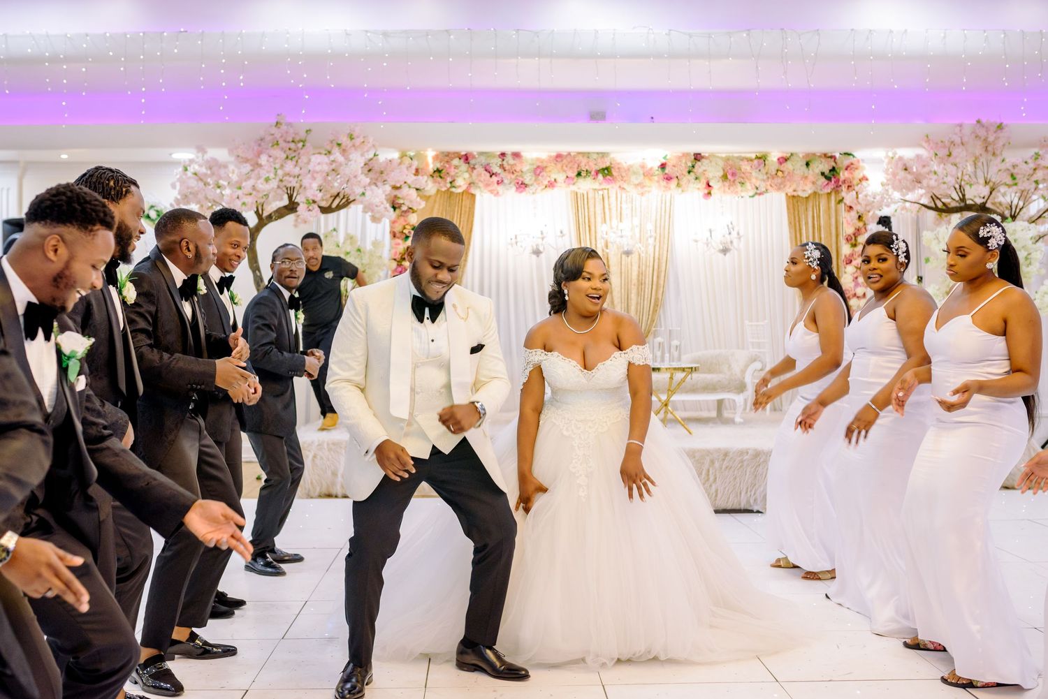 Wedding reception venue decorated in white with guests seated at round tables.