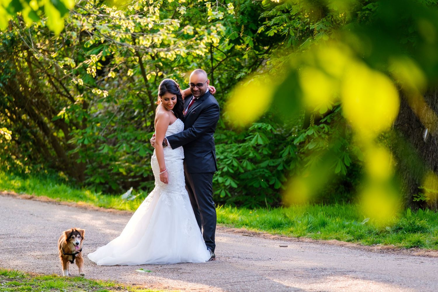 Newlywed couple poses for romantic outdoor photos in a sunlit garden setting.