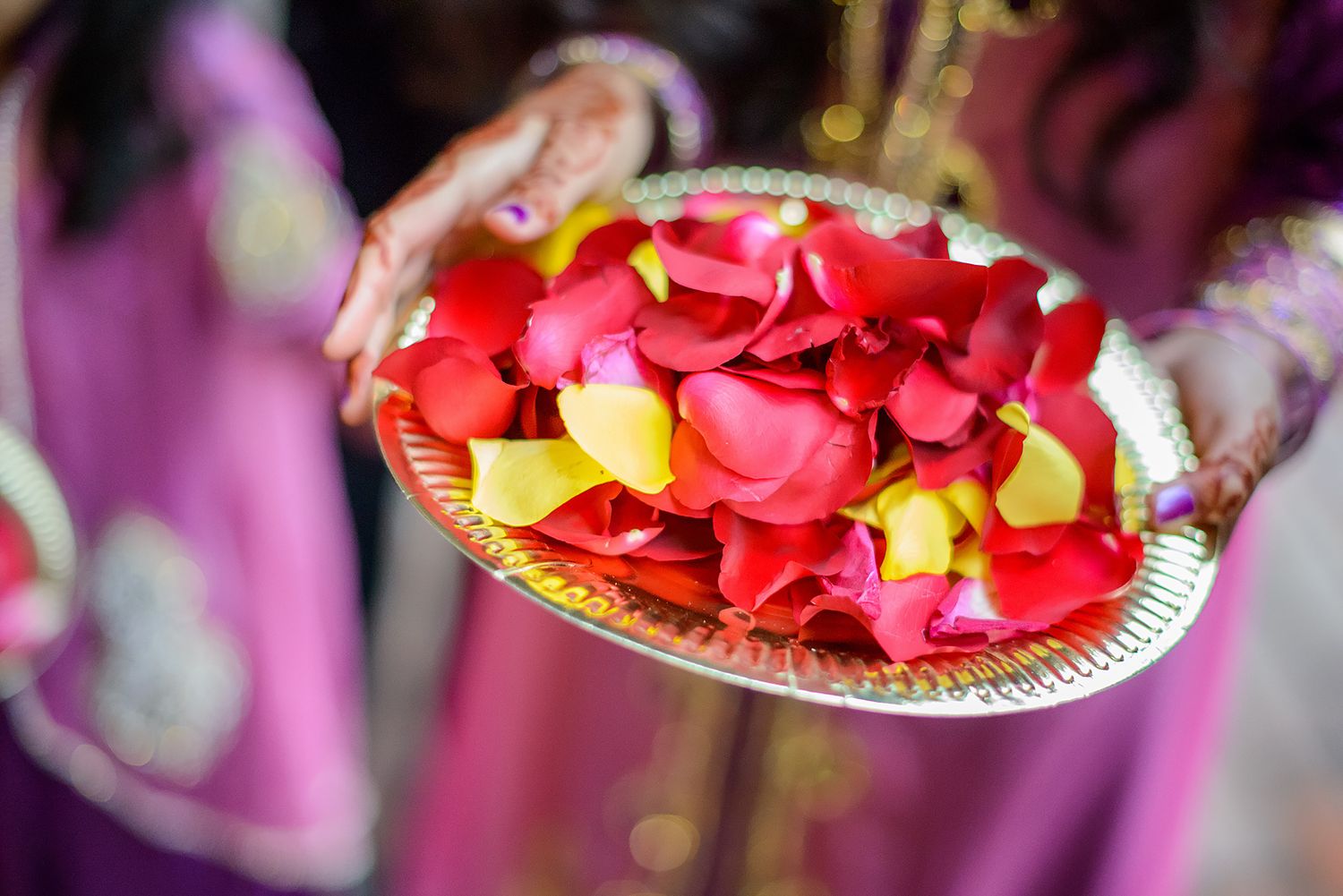 Vibrant red and pink rose petals arranged on decorative plates for an Indian wedding ceremony.